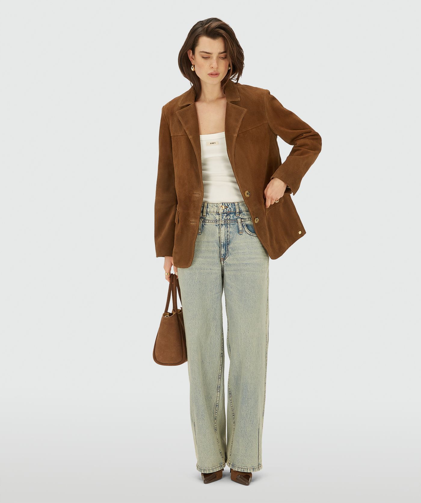 Model in een bruine suède blazer met knoopsluiting.