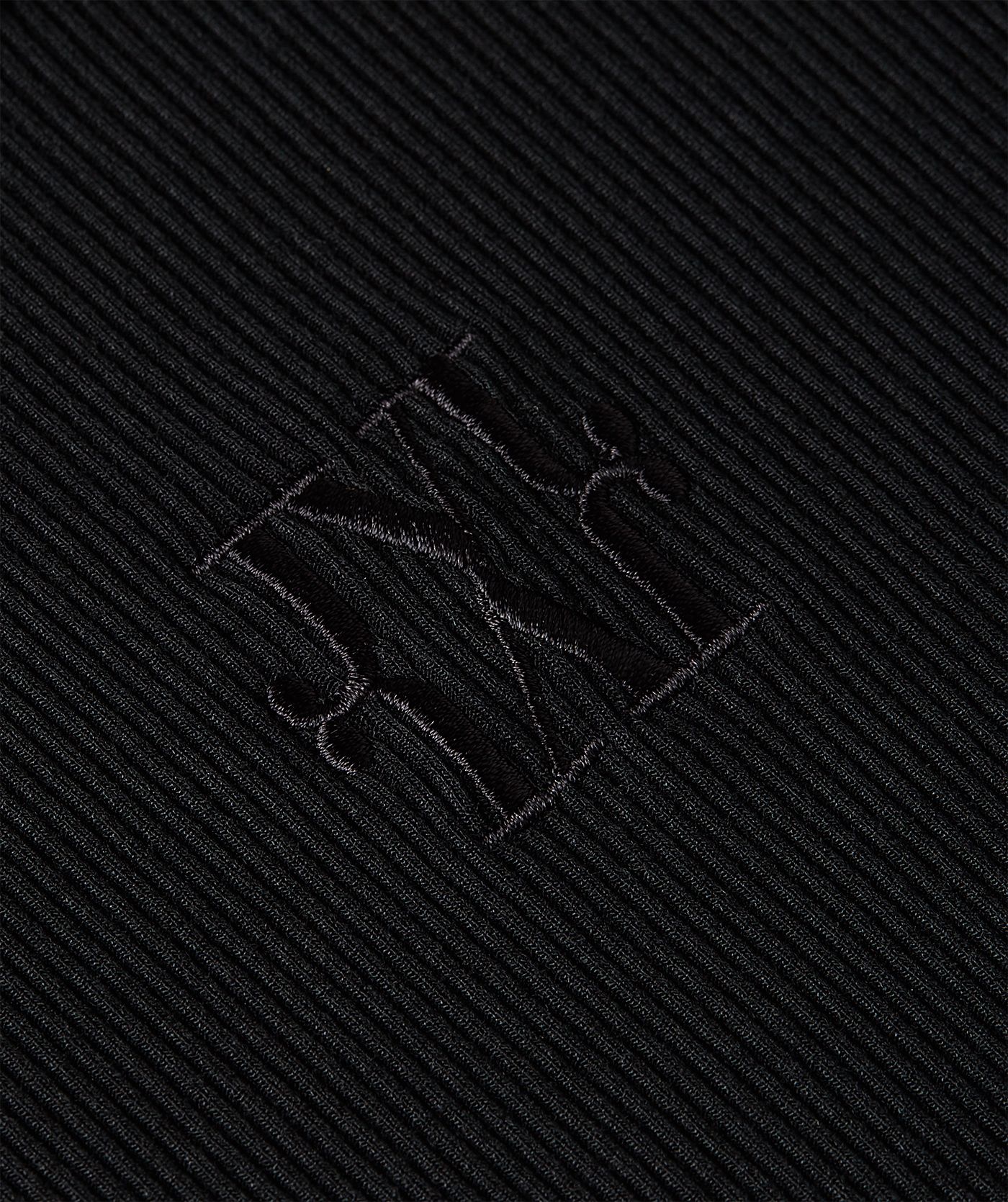 Close-up van een super fitted top in zwart, voorzien van een JOSH V-logo borduursel op de voorzijde