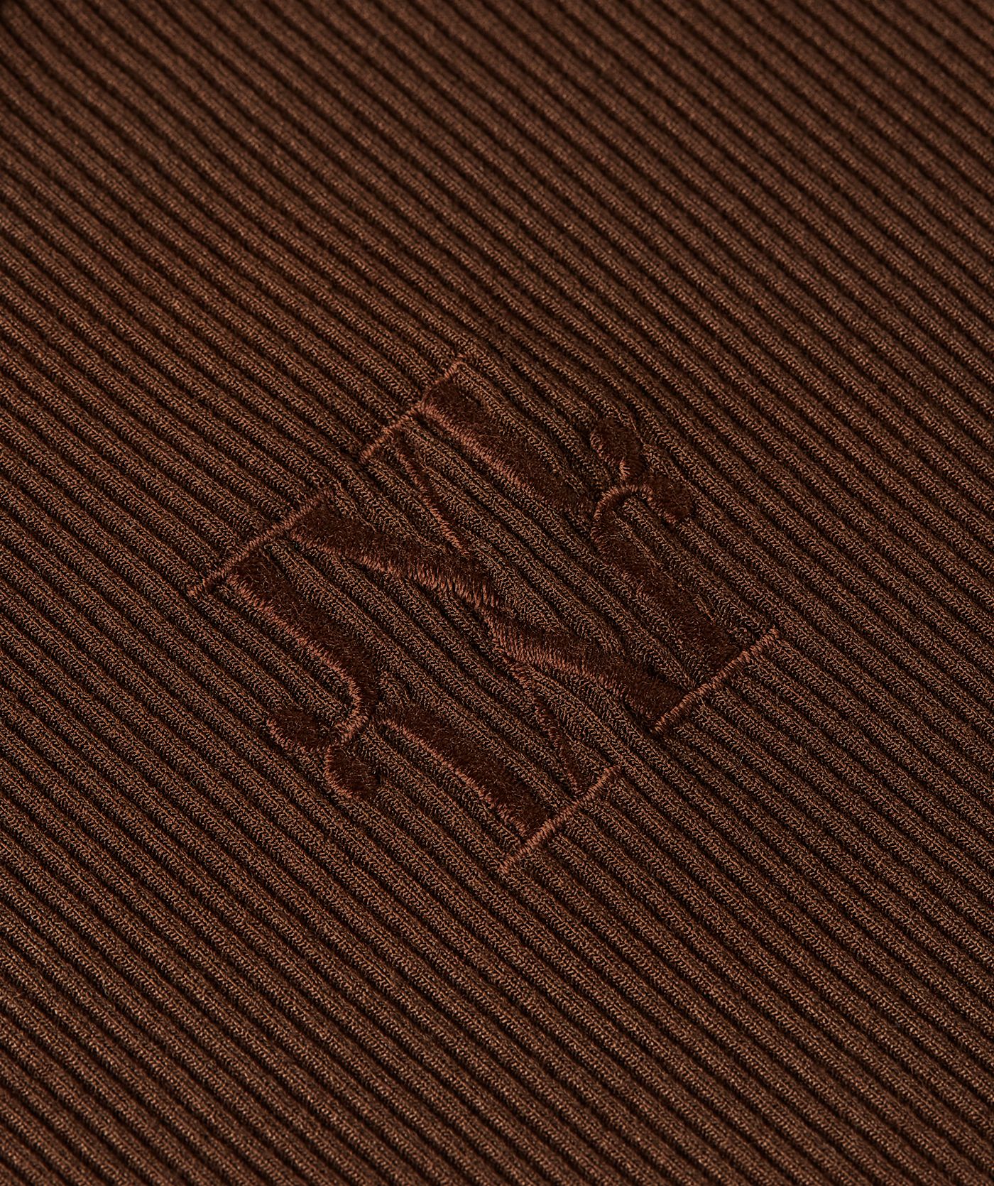 Close-up van het geborduurde JOSH V logo op een super fitted top in bruin