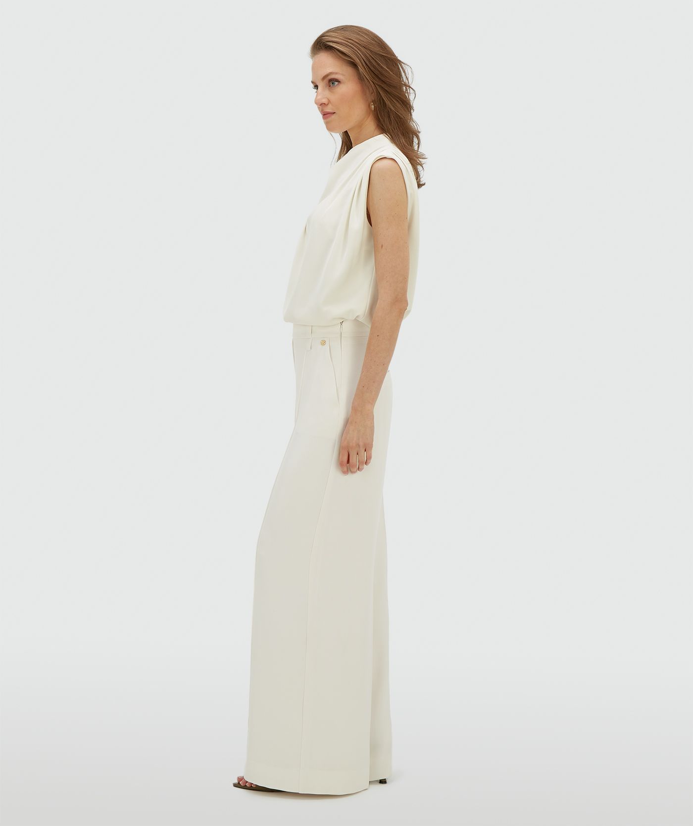 Zijaanzicht van een model in een high waisted wide leg pantalon in de kleur Off White