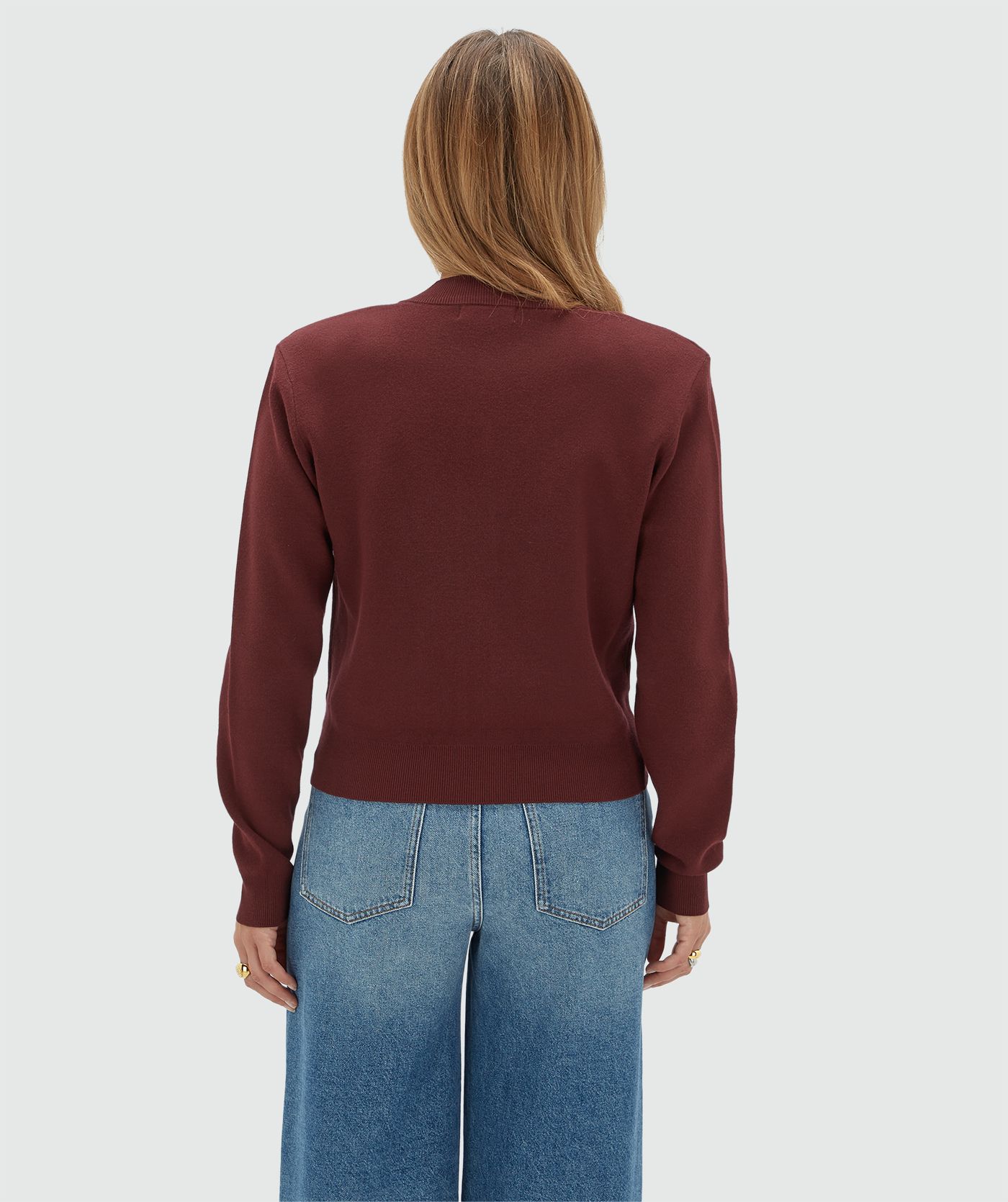 Achteraanzicht van een model in een donkerrood vest.