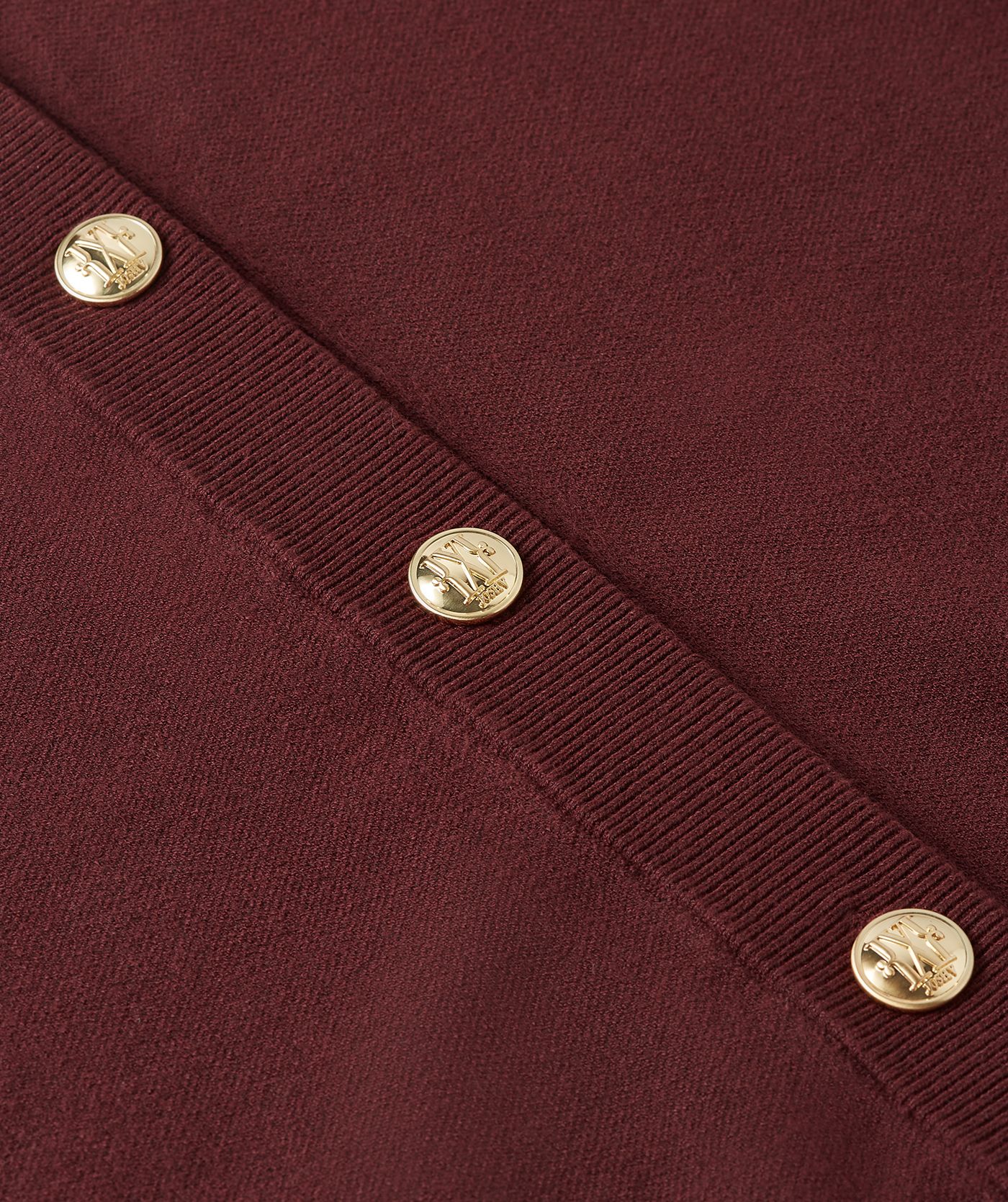 Close-up van de gouden knopen op het donkerrode vest.