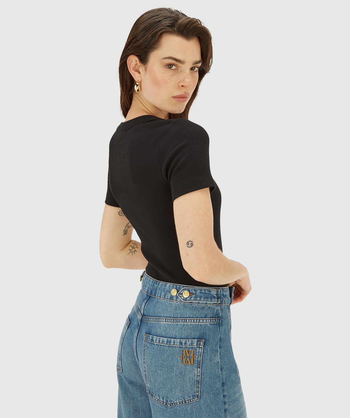 Achteraanzicht van een model in een Zwarte top met korte mouwen en een vierkante hals 