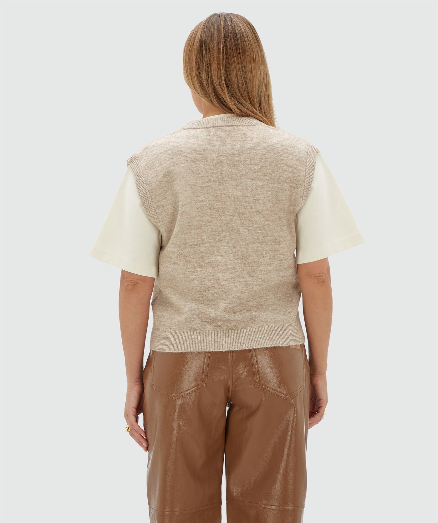 Achteraanzicht van een model in een beige gilet gecombineerd met een wot T-shirt.