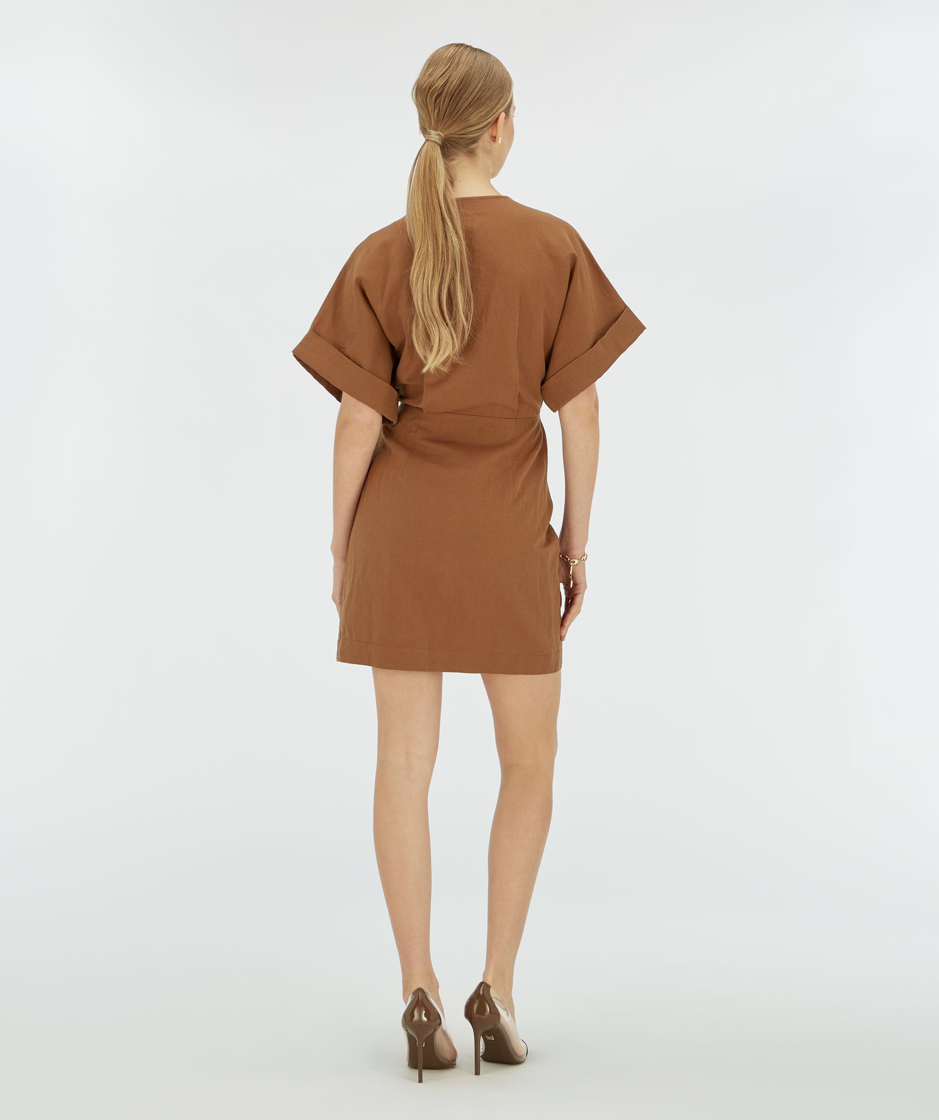 Achteraanzicht van een model in een donkerbruine overslagjurk.