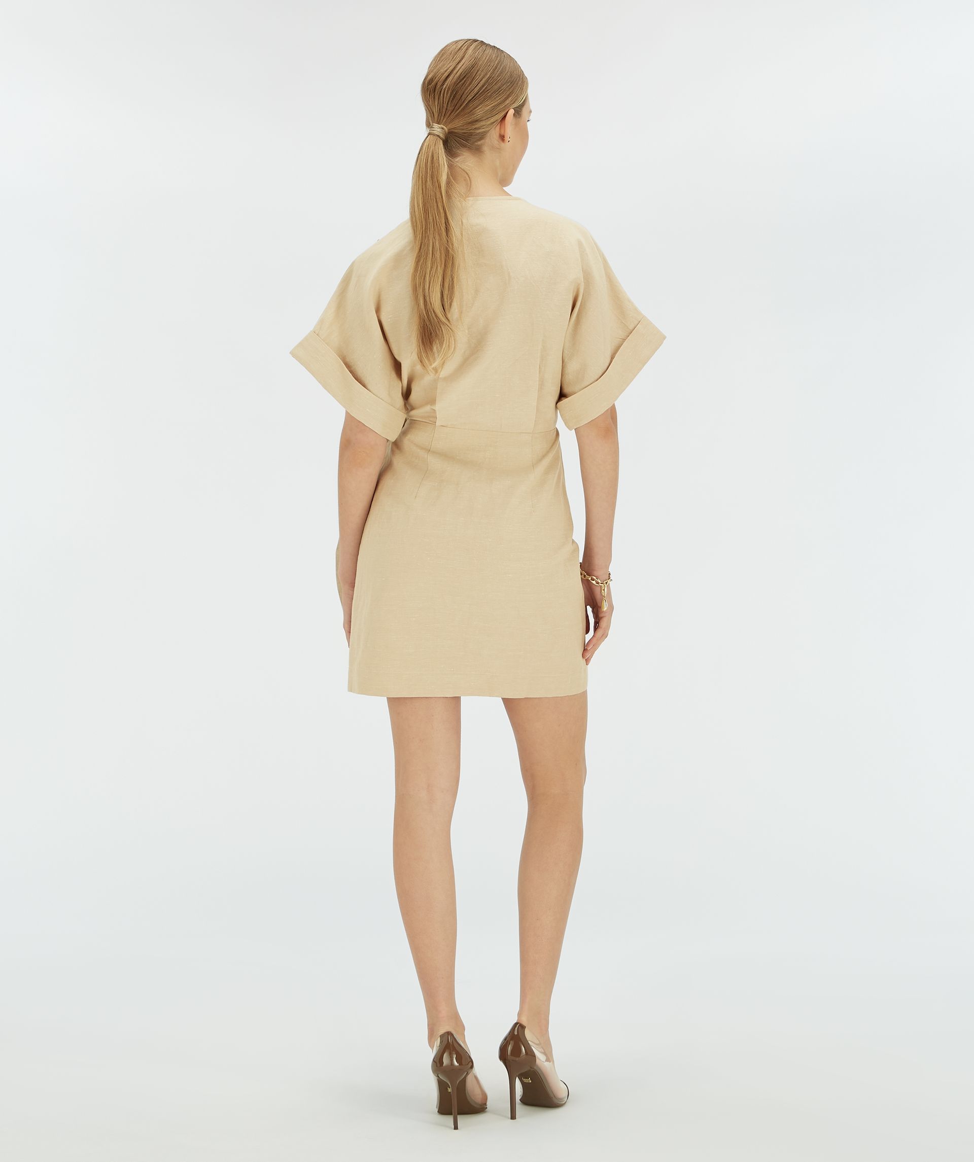 Achteraanzicht van een model in beige overslagjurk.
