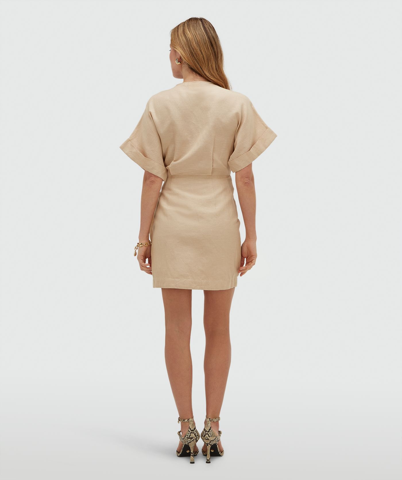 Achteraanzicht van een model in een overslagjurk met sierstenen in de kleur Oat