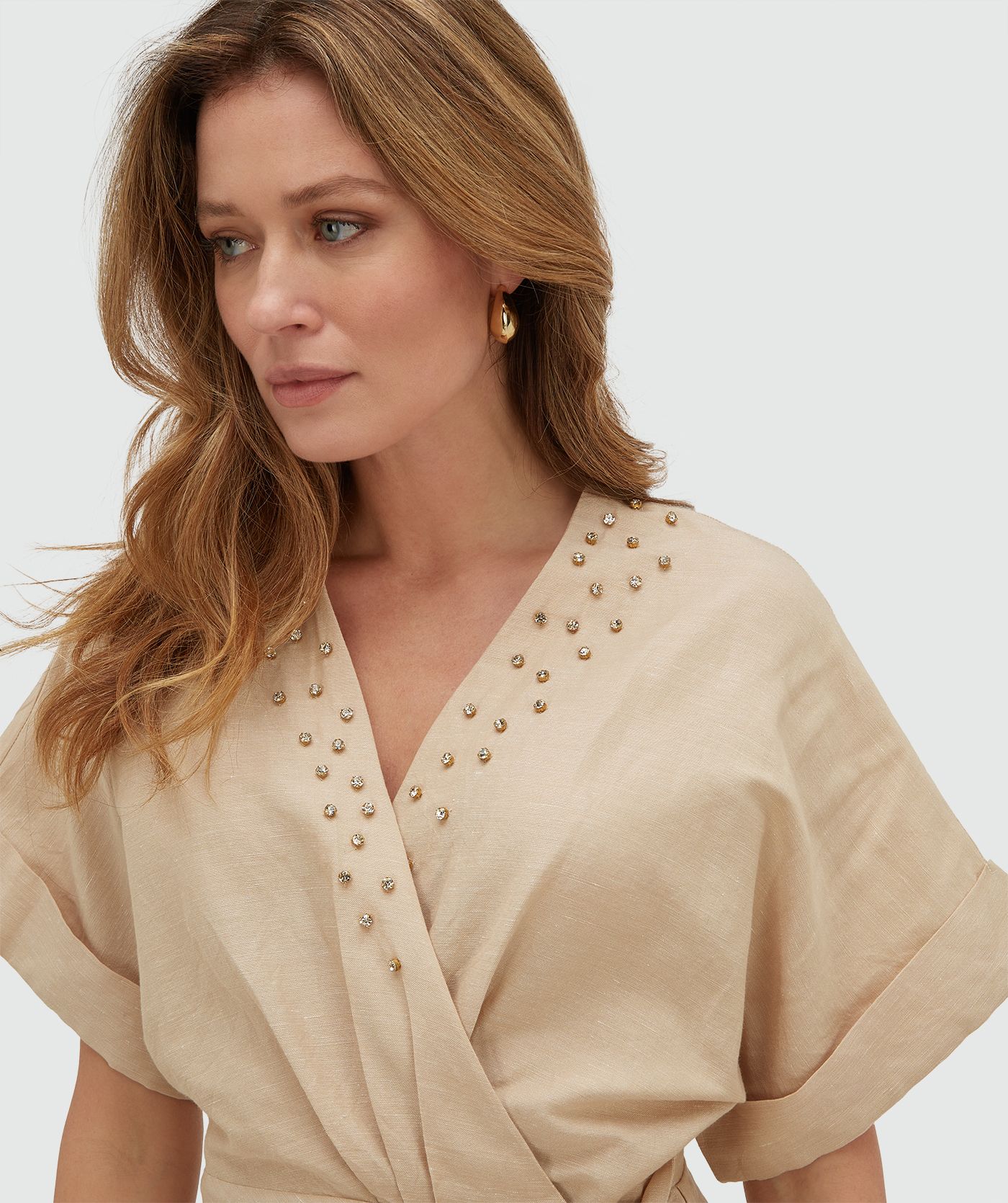 Model draagt een overslagjurk met sierstenen in de kleur Oat
