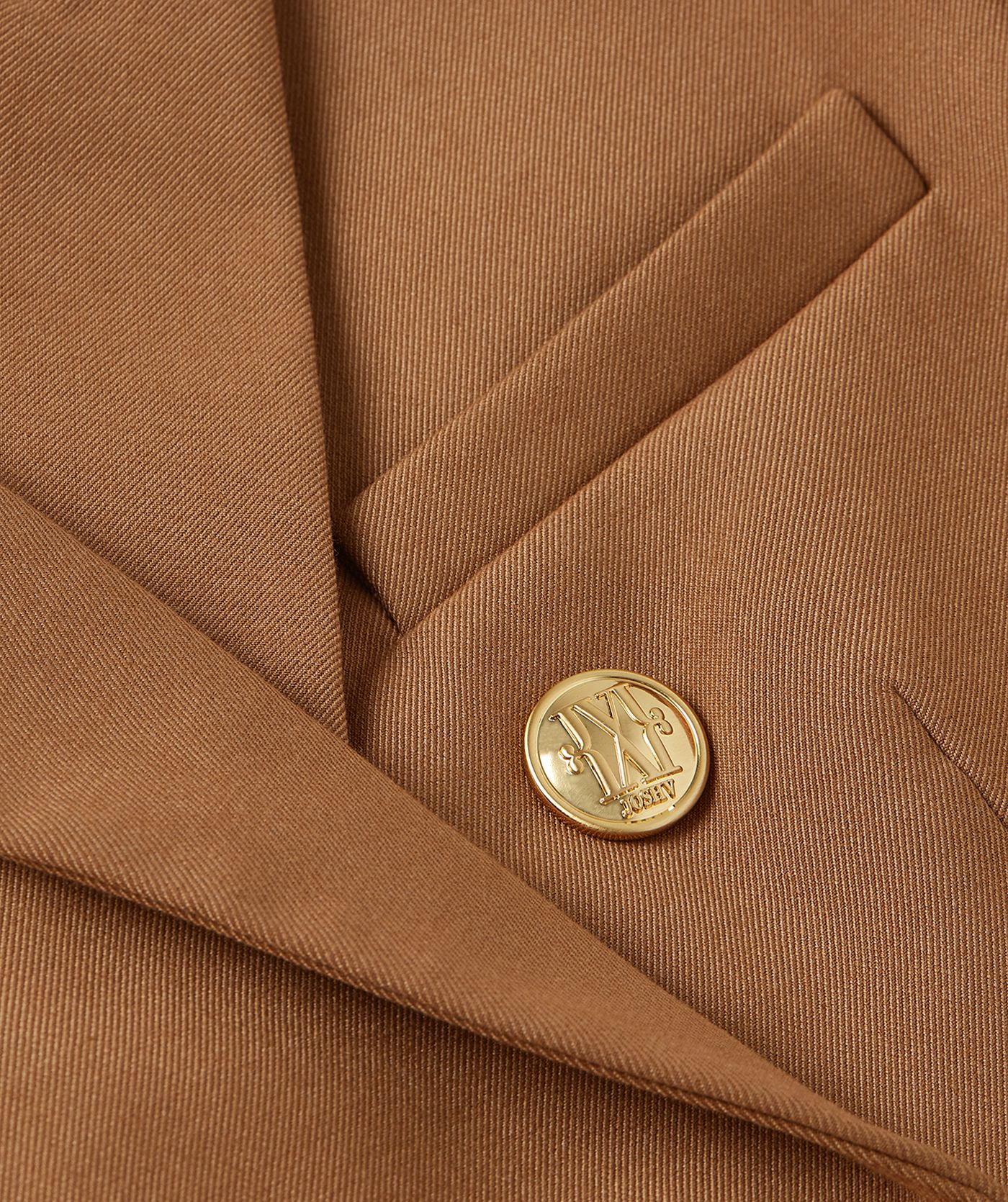 Close-up van een cognac kleurige blazer met gouden knopen