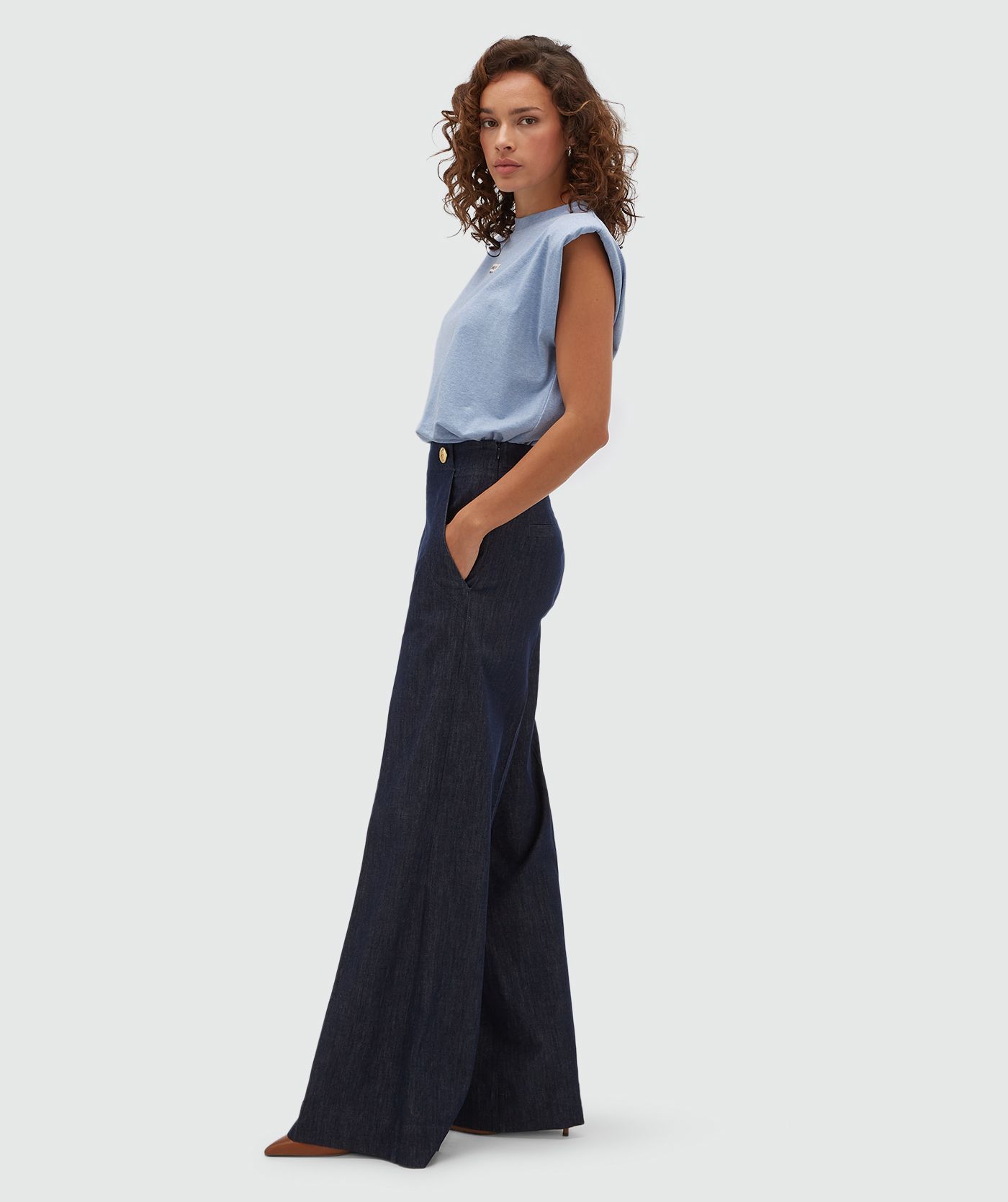 Model van opzij in in een donkerblauwe pantalon.