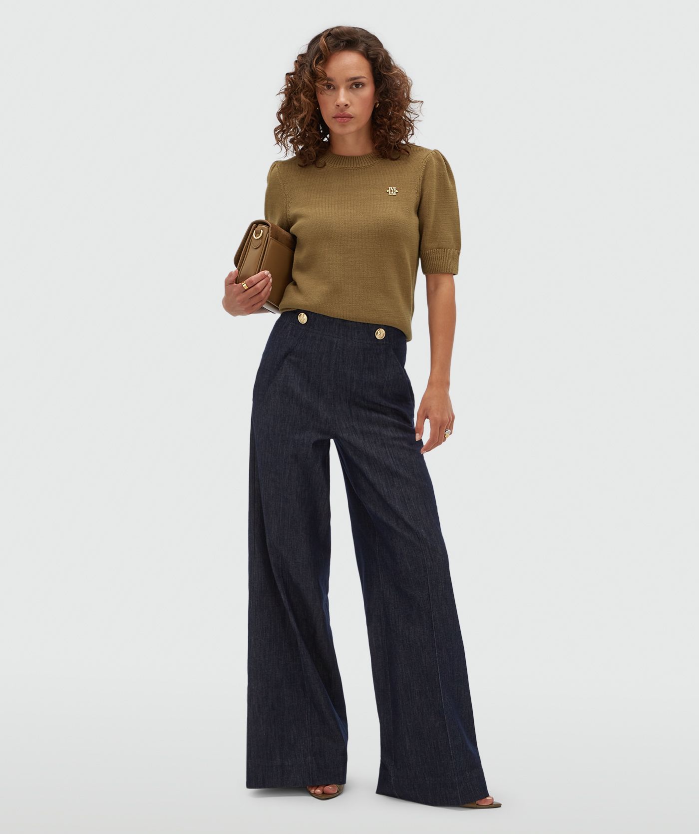 Model draagt een donkerblauwe wide leg pantalon met gouden knopen aan de bovenkant.