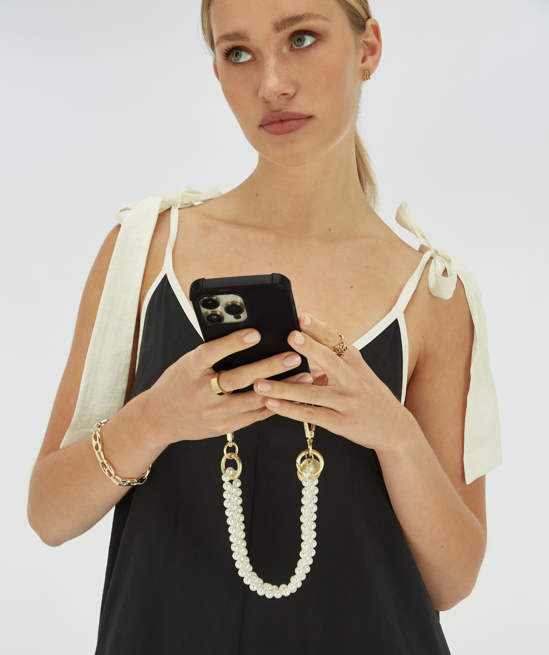 Model houdt een telefoon vast met daaraan de parel telefoonkoord.