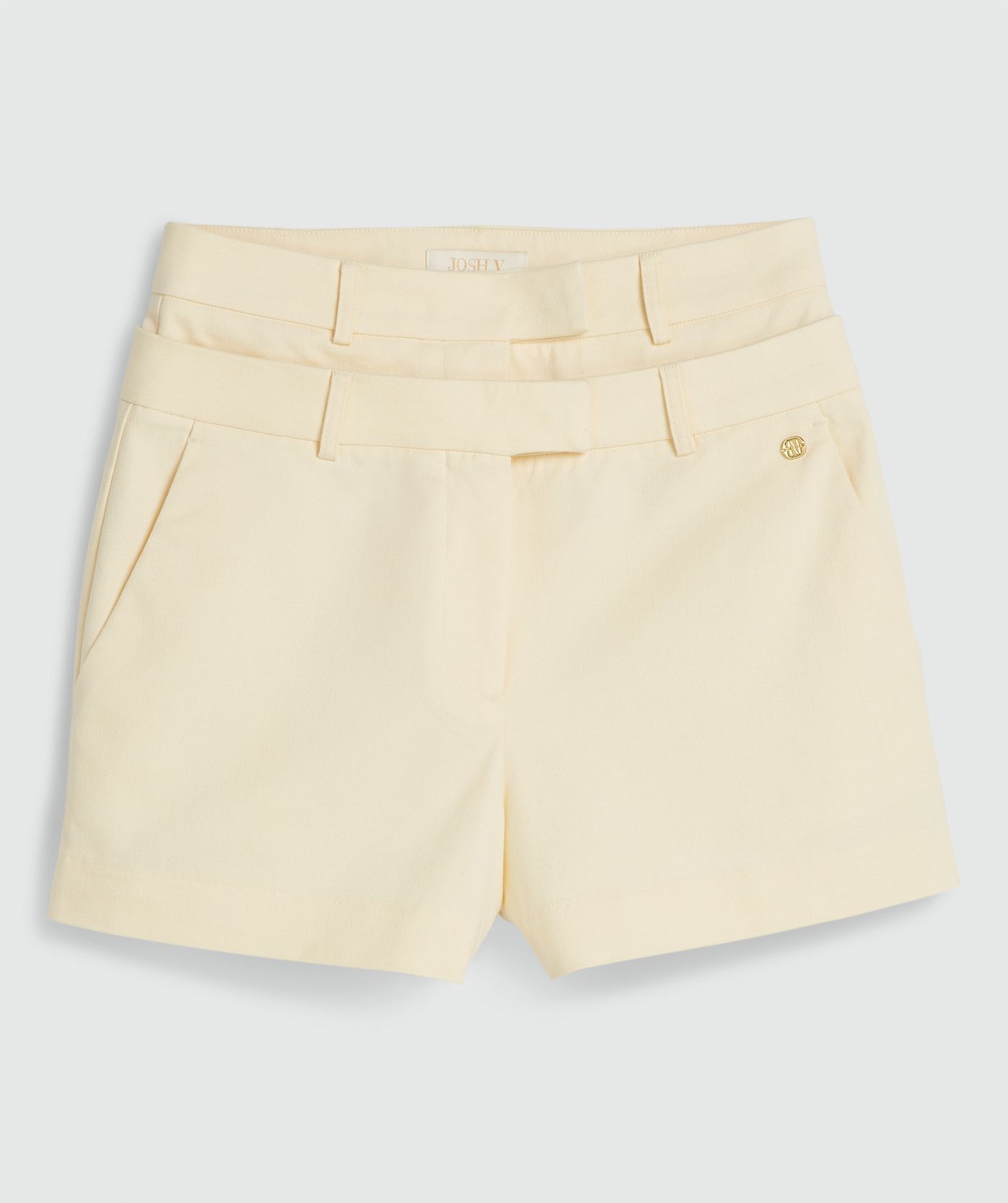 Een high waisted short in de kleur Butter Yellow, zonder model, weergegeven op een lichtgrijze achtergrond