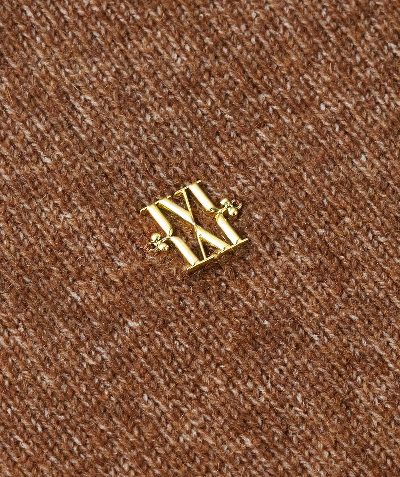Close-up van gouden JOSH V logo op de bruin trui.