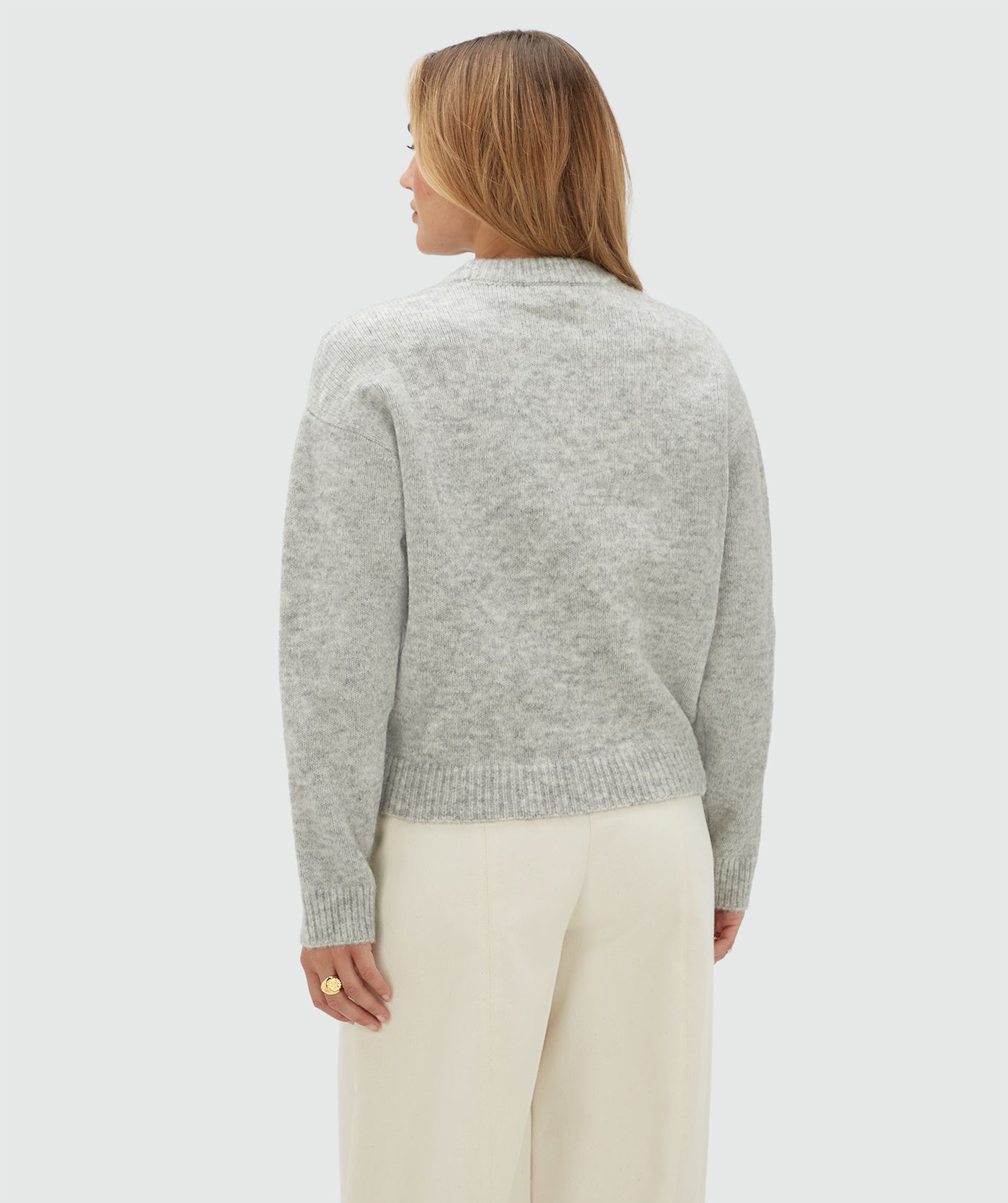 Achteraanzicht van een model in een lichtgrijze sweater.