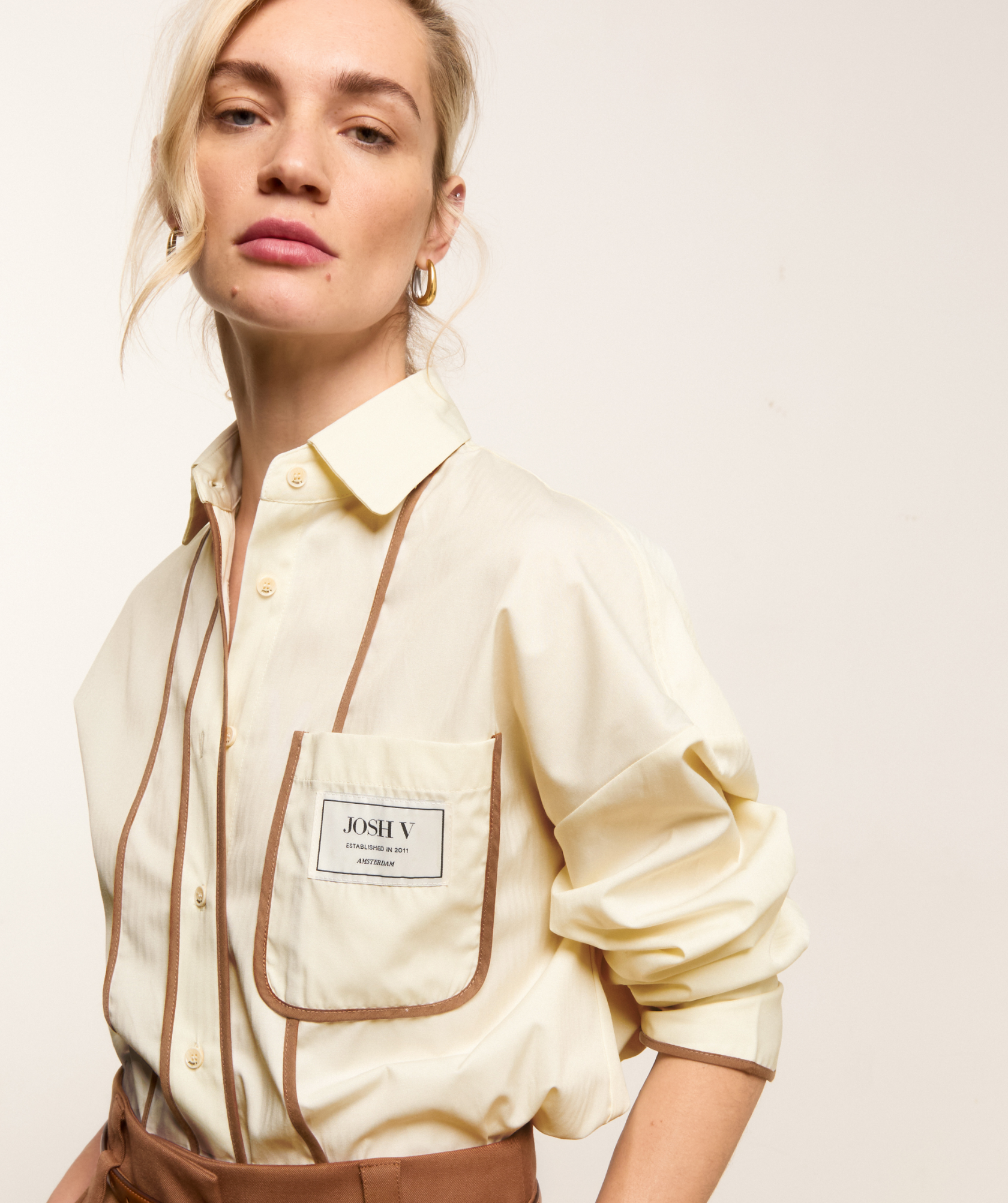 Lookbook beeld waar het model een oversized blouse draagt met bruine details