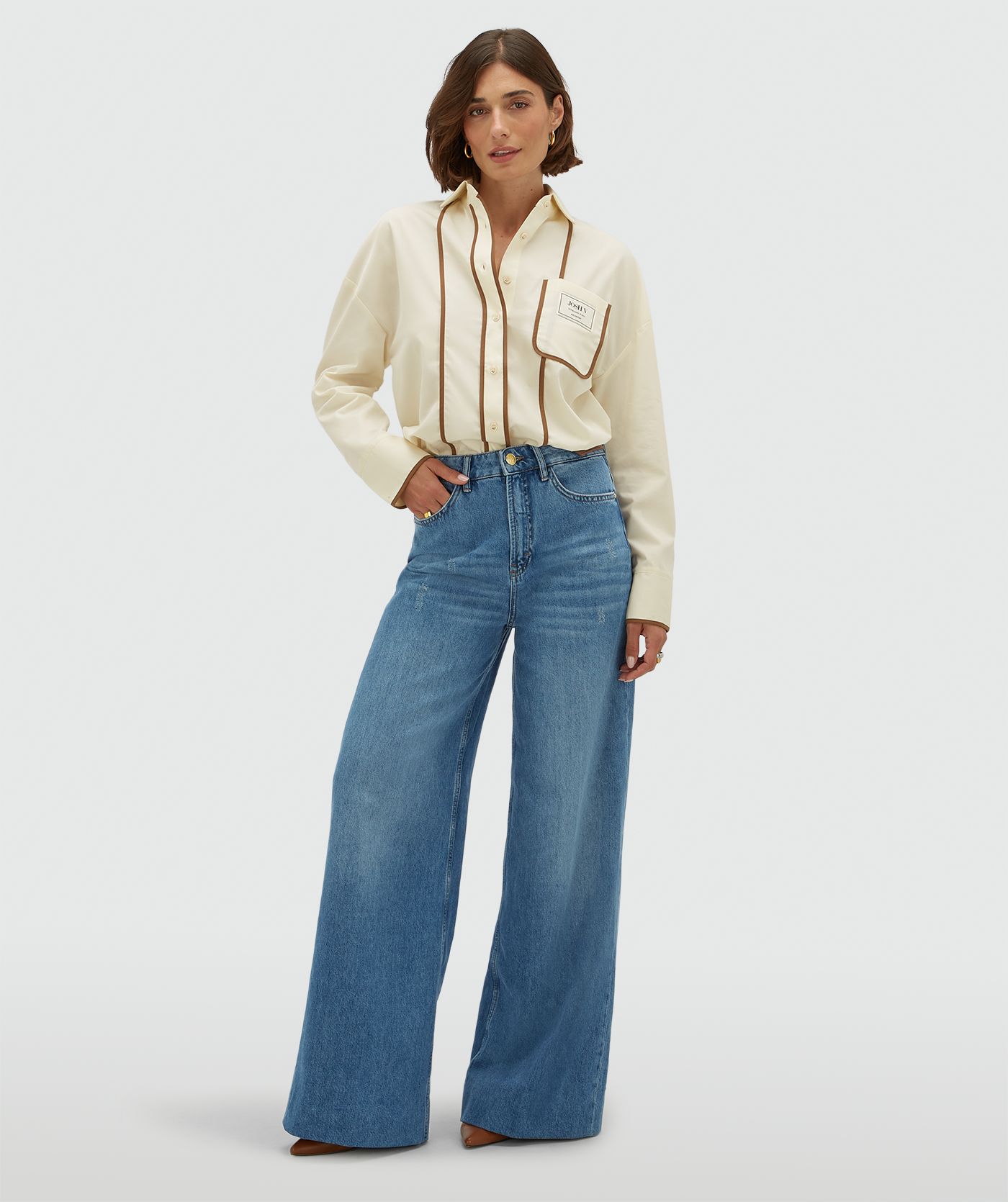Model draagt een oversized witte blouse met bruine details