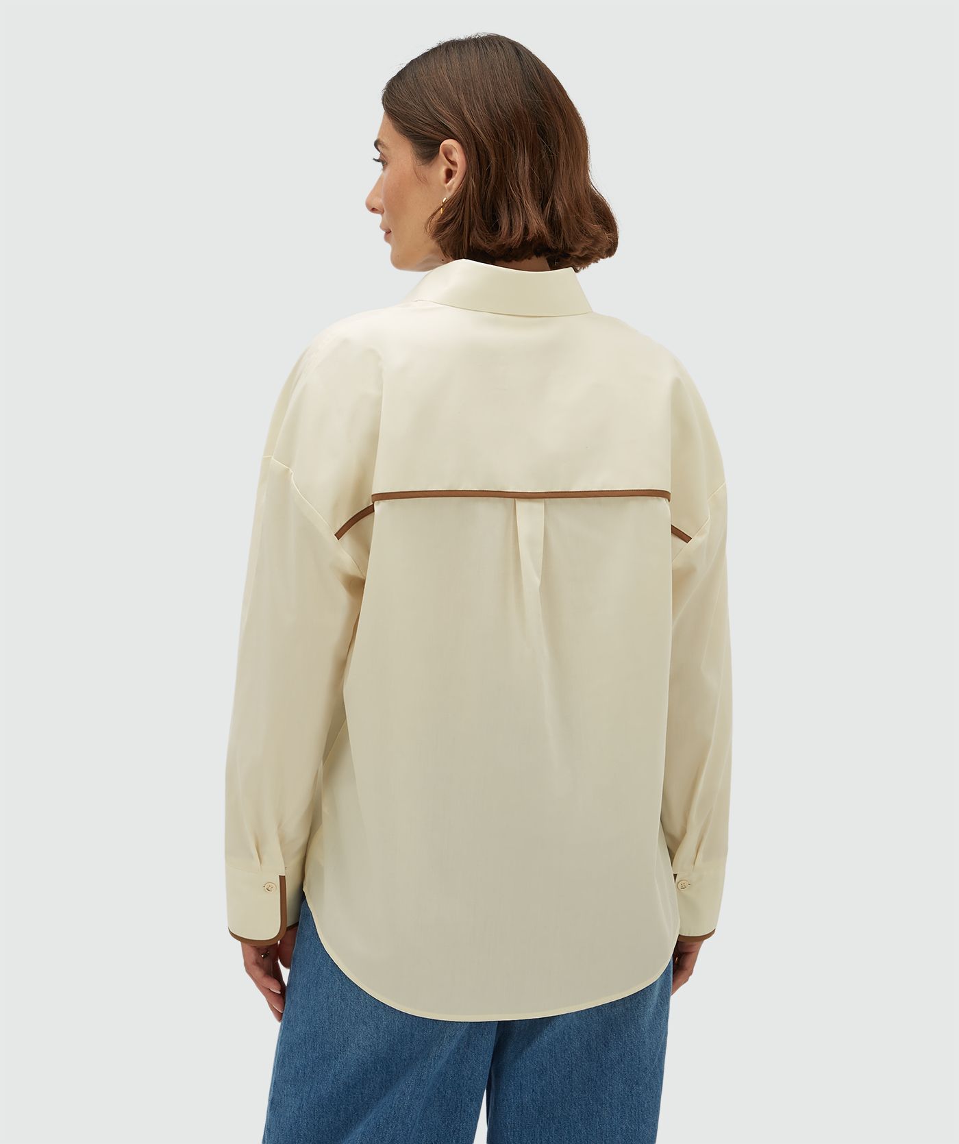Achteraanzicht van een model in een oversized blouse met bruine details