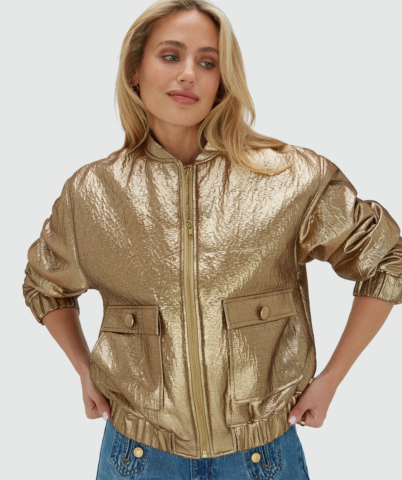 Model draagt een oversized bomber jacket in metallic in de kleur Bronze Gold met de rits dicht