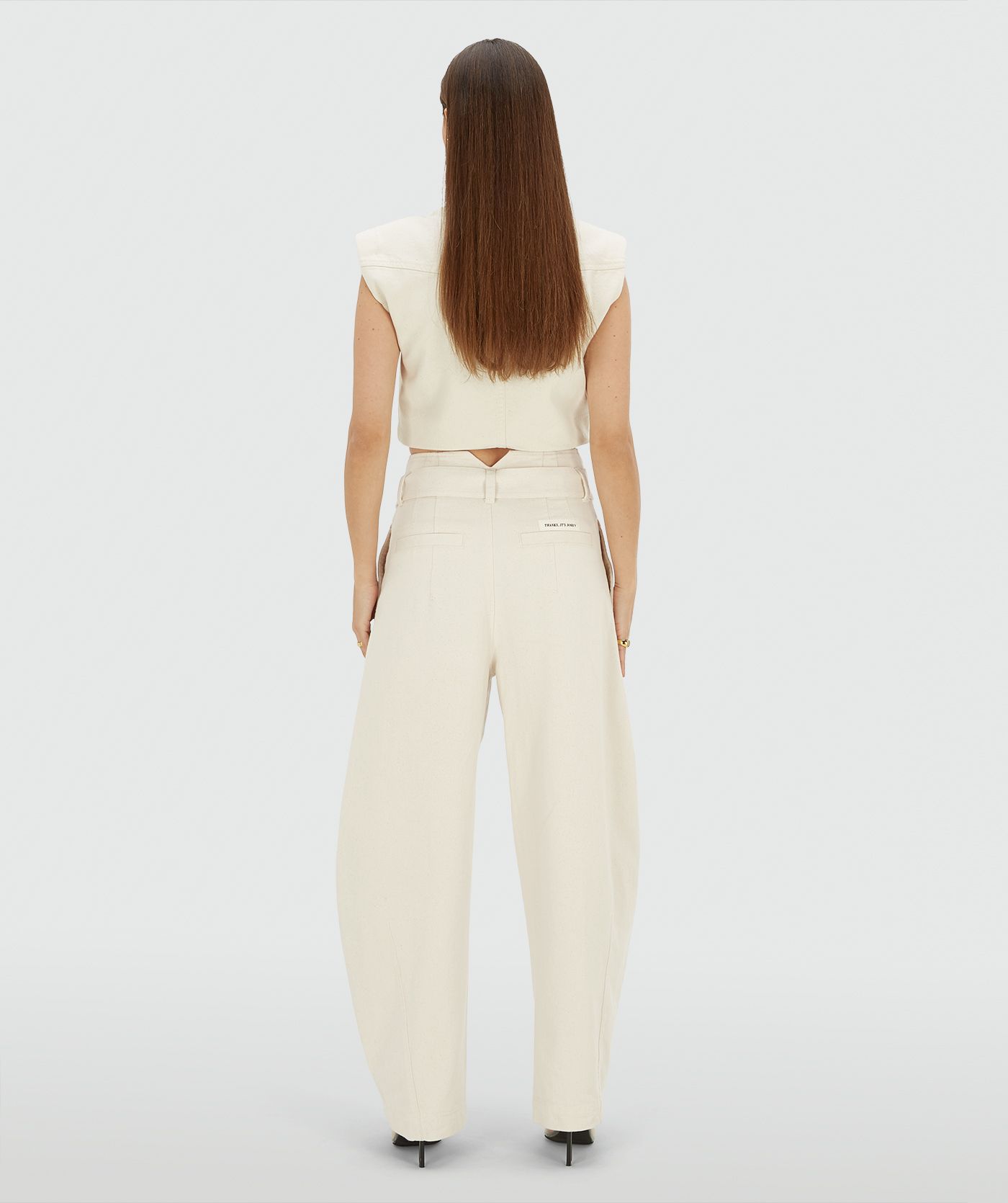 Achteraanzicht van een model in een high waisted balloon fit broek met strikdetail in de waistband in de kleur Ecru