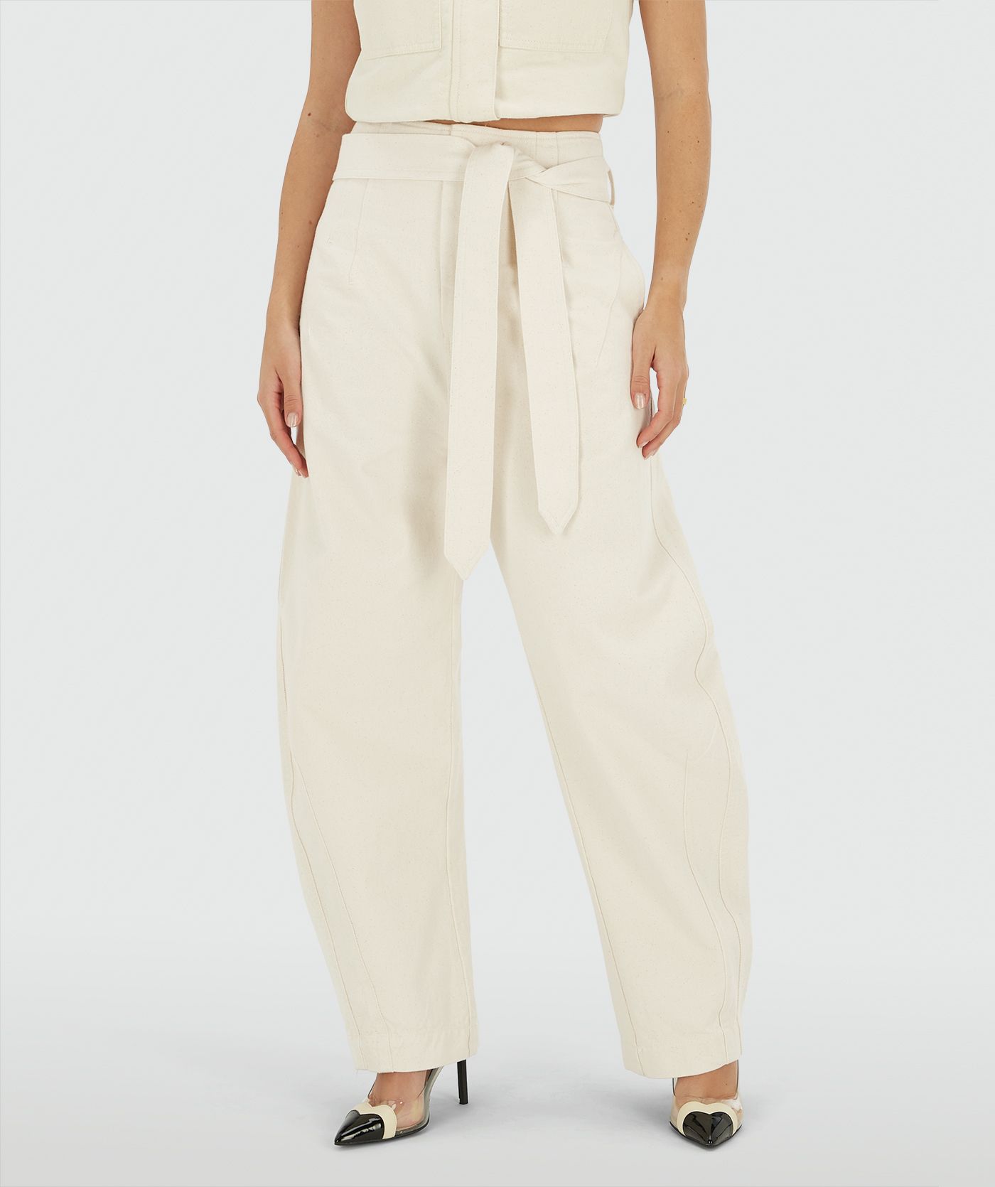 Model draagt een high waisted balloon fit broek met strikdetail in de waistband in de kleur Ecru