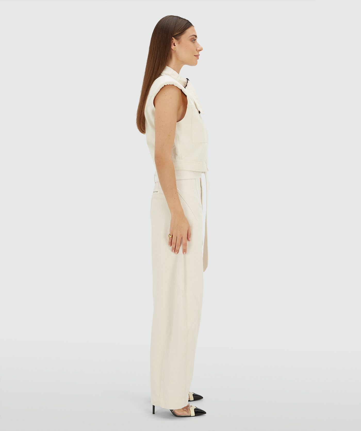 Zijaanzicht van een model in een high waisted balloon fit broek met strikdetail in de waistband in de kleur Ecru