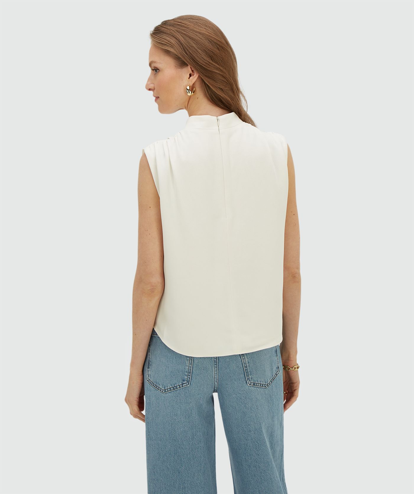 Achteraanzicht van een model in een losvallende top in de kleur Off White