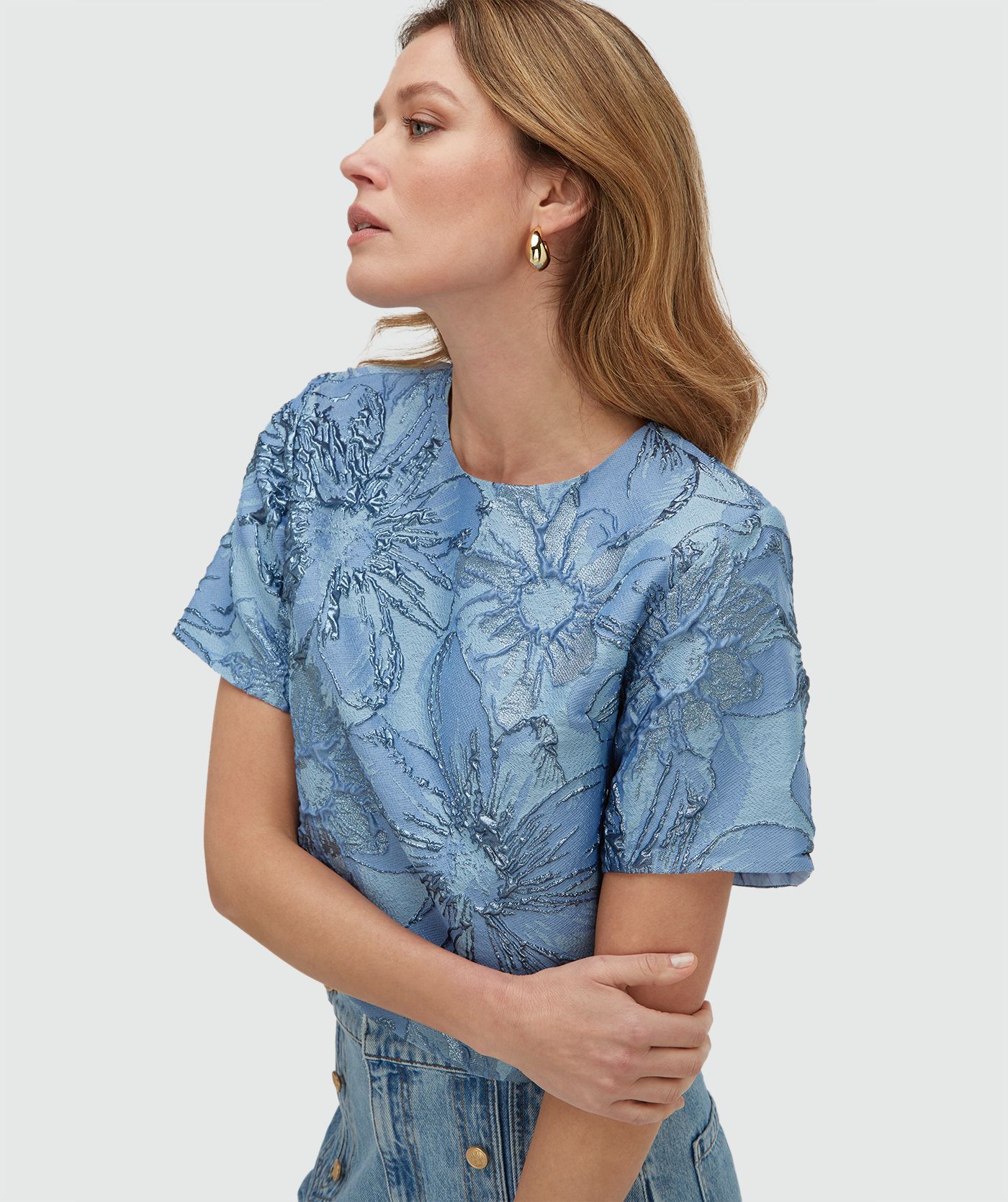 Model draagt een cropped top met metallic details in de kleur Fresh Blue