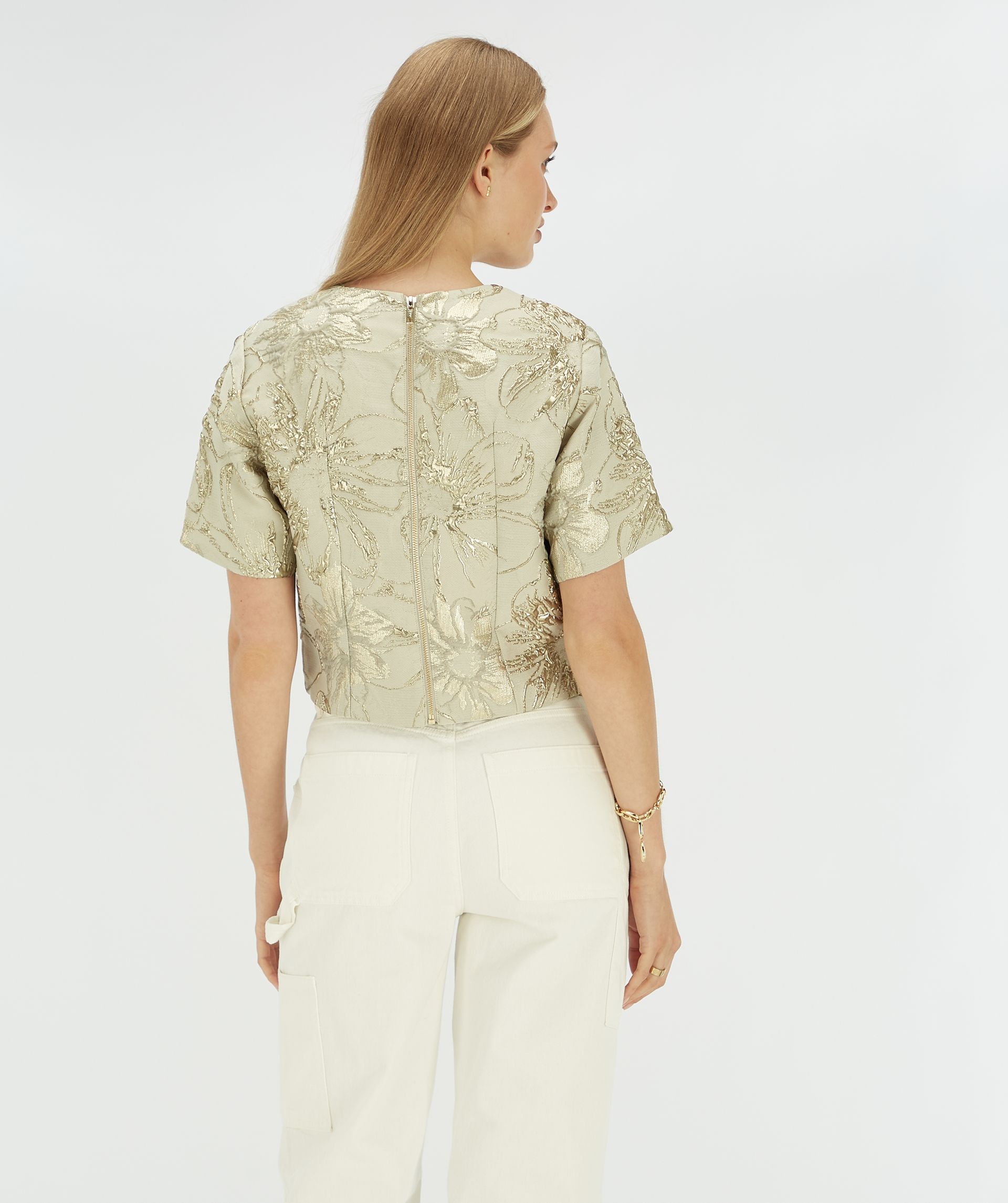 Achteraanzicht van een model in een cropped top met bloemen print.