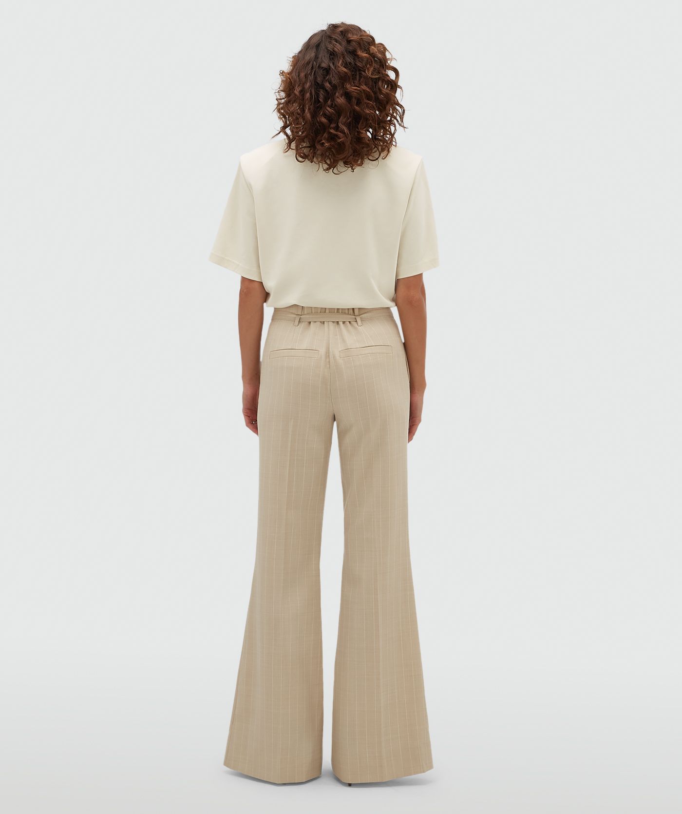 Achteraanzicht van een model in een beige flared pantalon met krijtstreep.