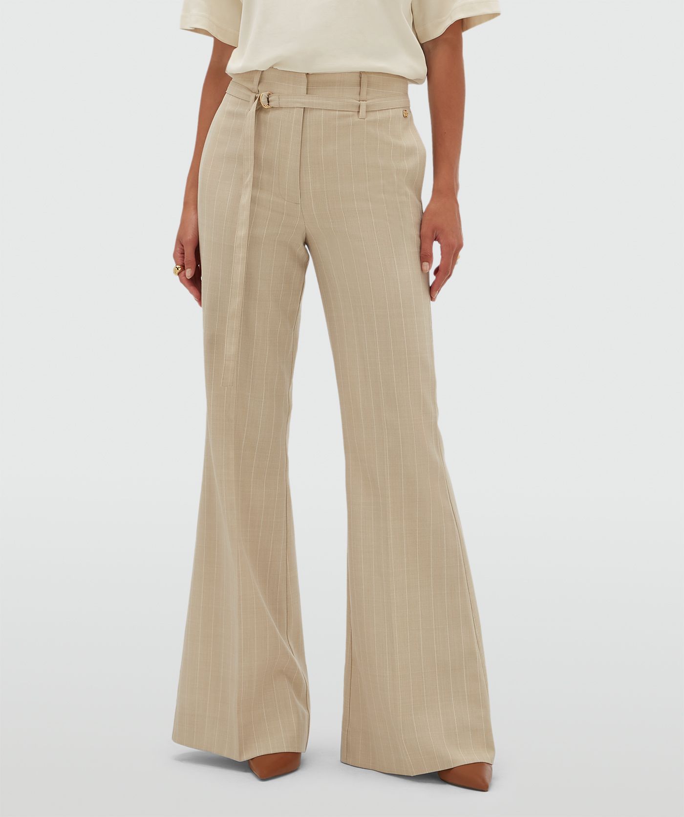 Model draagt een beige flared pantalon met krijtstreep.