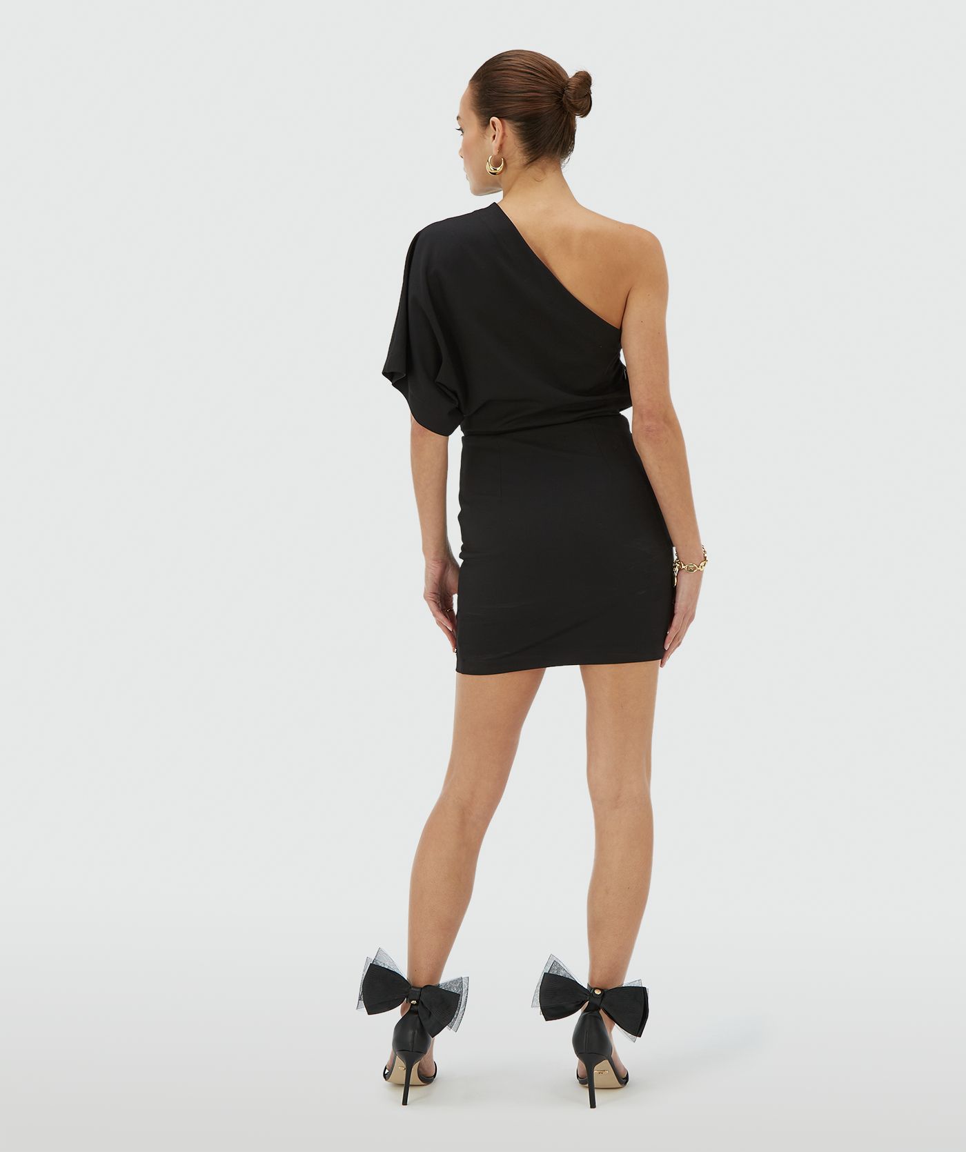 Achteraanzicht van een model in een aangesloten zwarte one shoulder jurk met asymmetrische halslijn - JOSH V