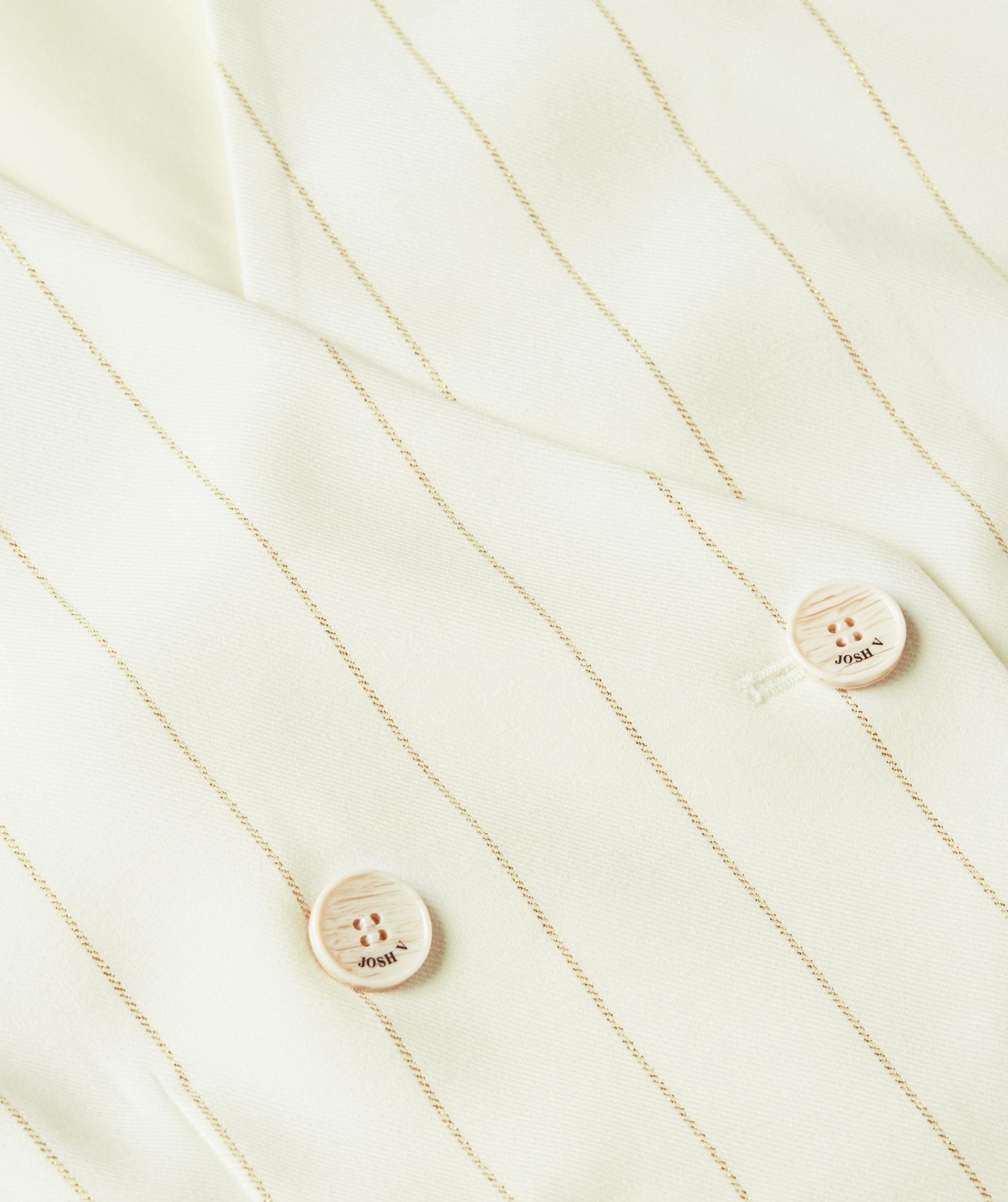Close-up van de knopen op het witte gilet met een beige krijtstreepje.