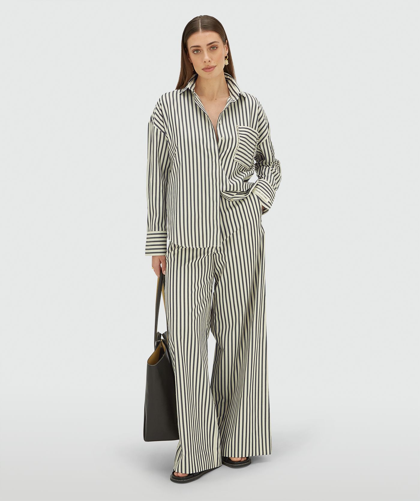 Model draagt een oversized blouse met strepen in de kleur Blue Stripe met strass steentjes rond de borstzak