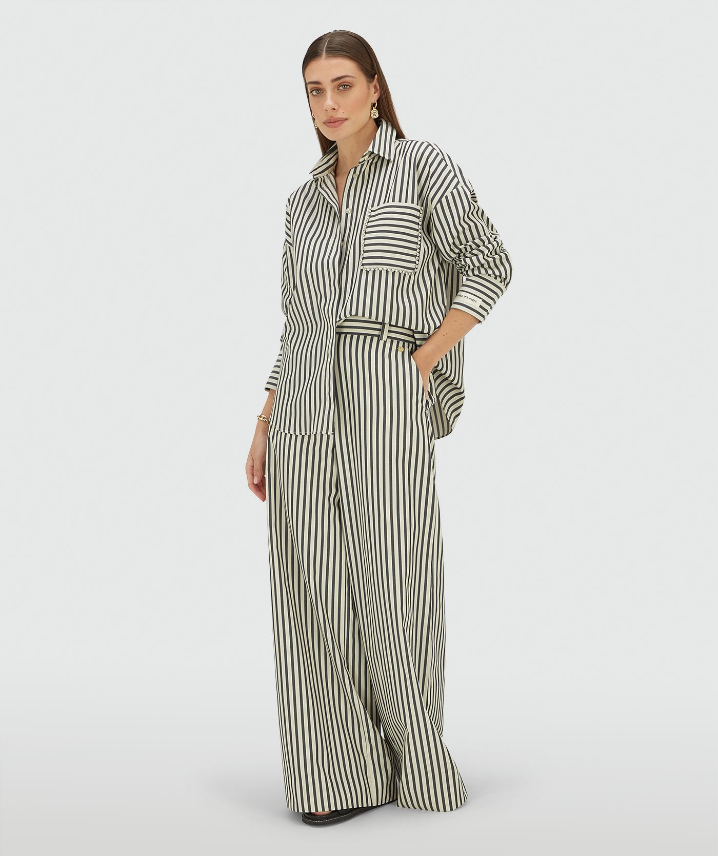 Model draagt een oversized blouse met strepen in de kleur Blue Stripe met strass steentjes rond de borstzak
