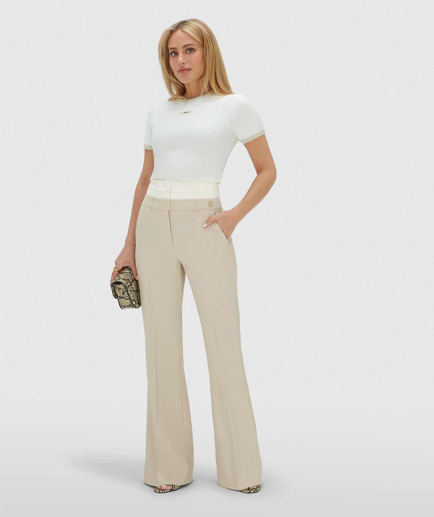 Model draagt een high rise flared pantalon met een dubbele band in de kleur Ecru Melange, hierbij is de bovenste band van de pantalon in Ecru en de rest van de broek in de kleur Melange