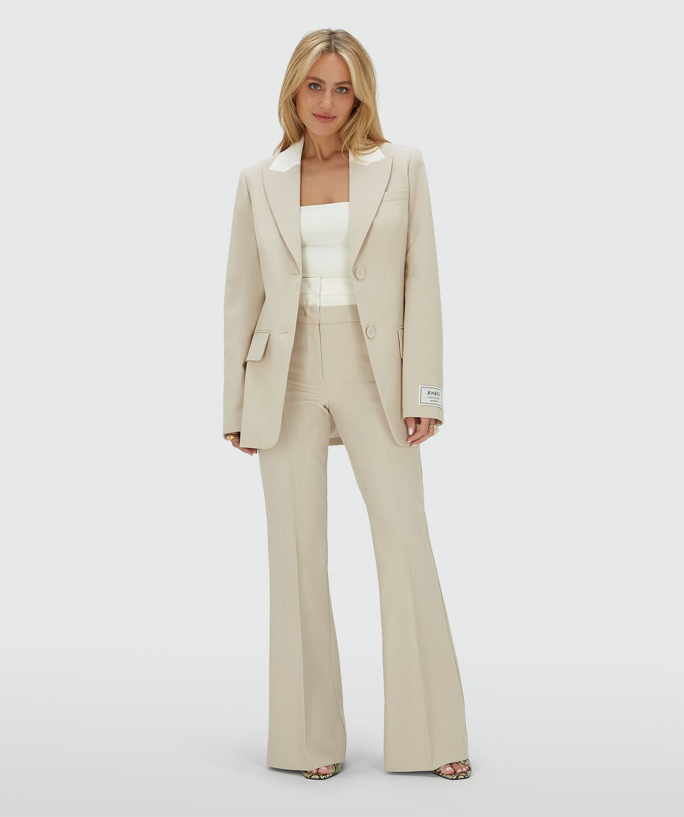 Model draagt een high rise flared pantalon met een dubbele band in de kleur Ecru Melange, hierbij is de bovenste band van de pantalon in Ecru en de rest van de broek in de kleur Melange