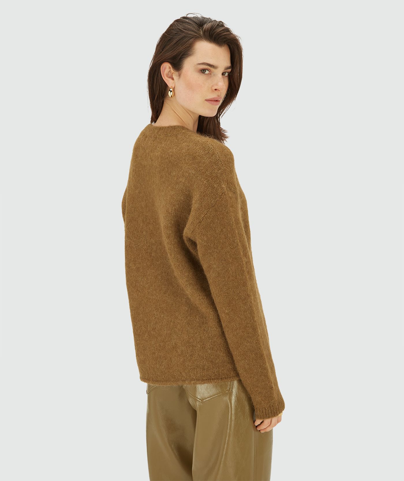 Achteraanzicht van model in een Olive Green Melange trui met ronde hals en lange mouwen, afgewerkt met een klein goudkleurig logo op de borst.