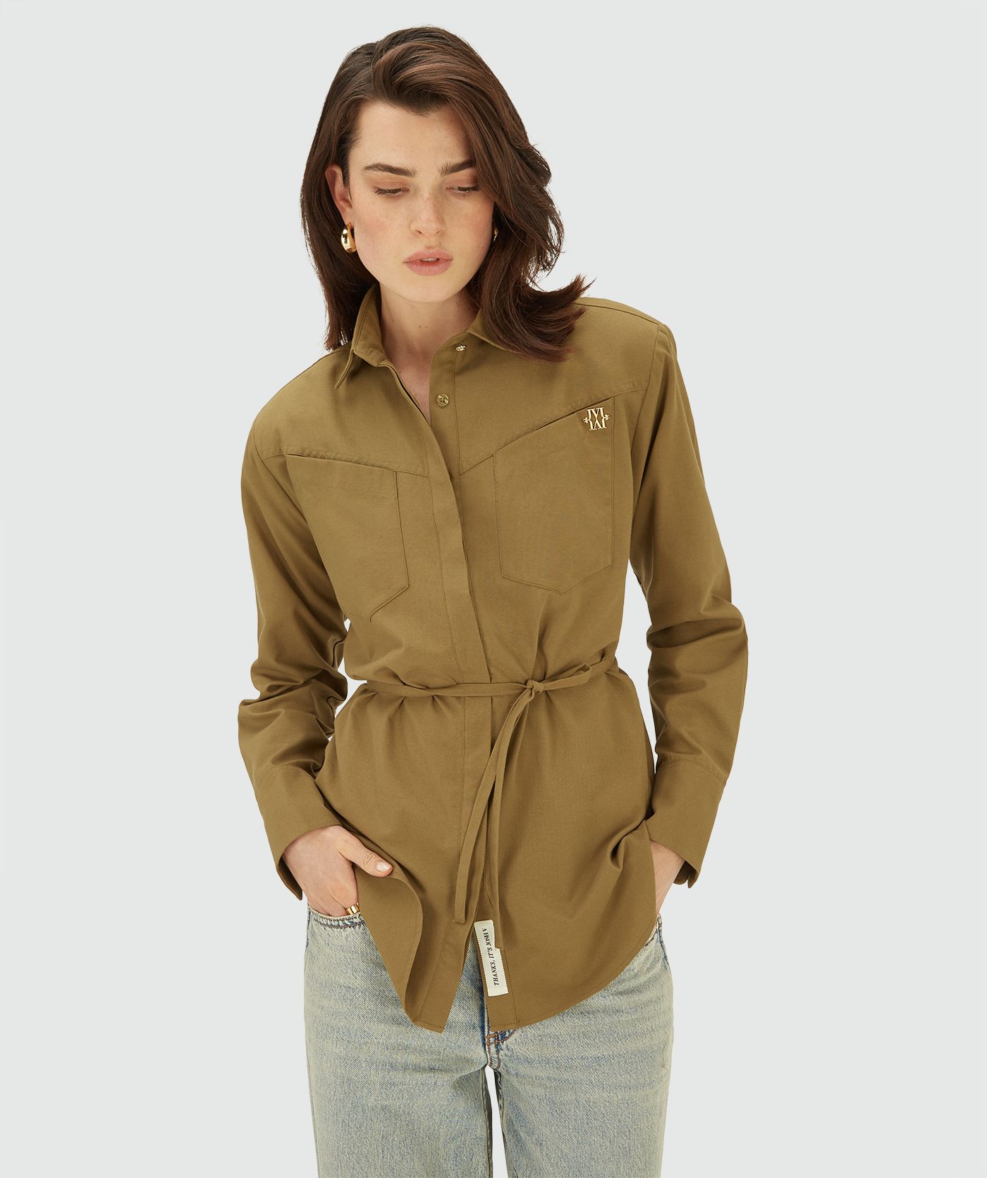 Model draagt een Olive Green blouse met lange mouwen, knoopsluiting en twee borstzakken. Het overhemd heeft een getailleerde pasvorm en een subtiel goudkleurig JOSH V-logo op de borst