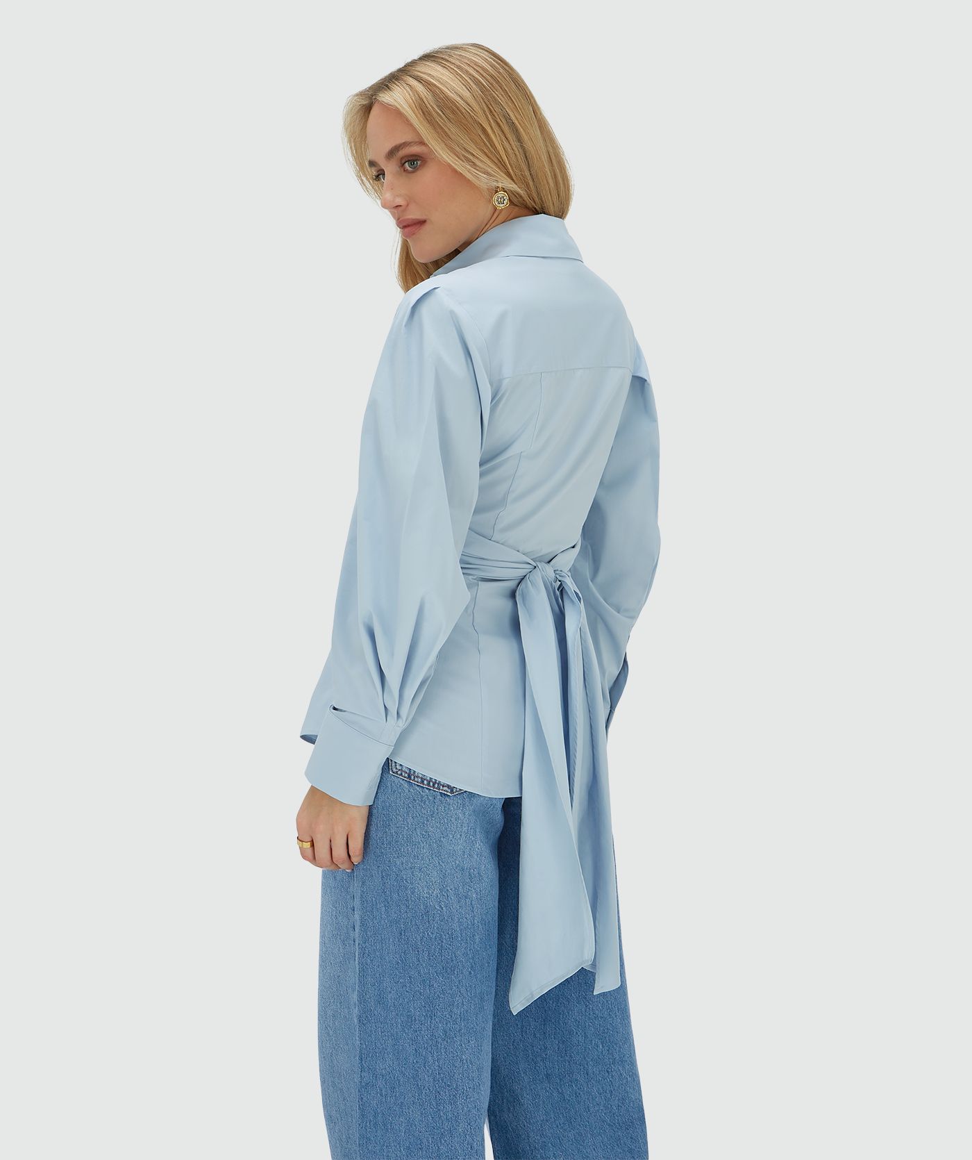 Achteraanzicht van een model in een fitted blouse in het blauw met strikdetail op de achterkant