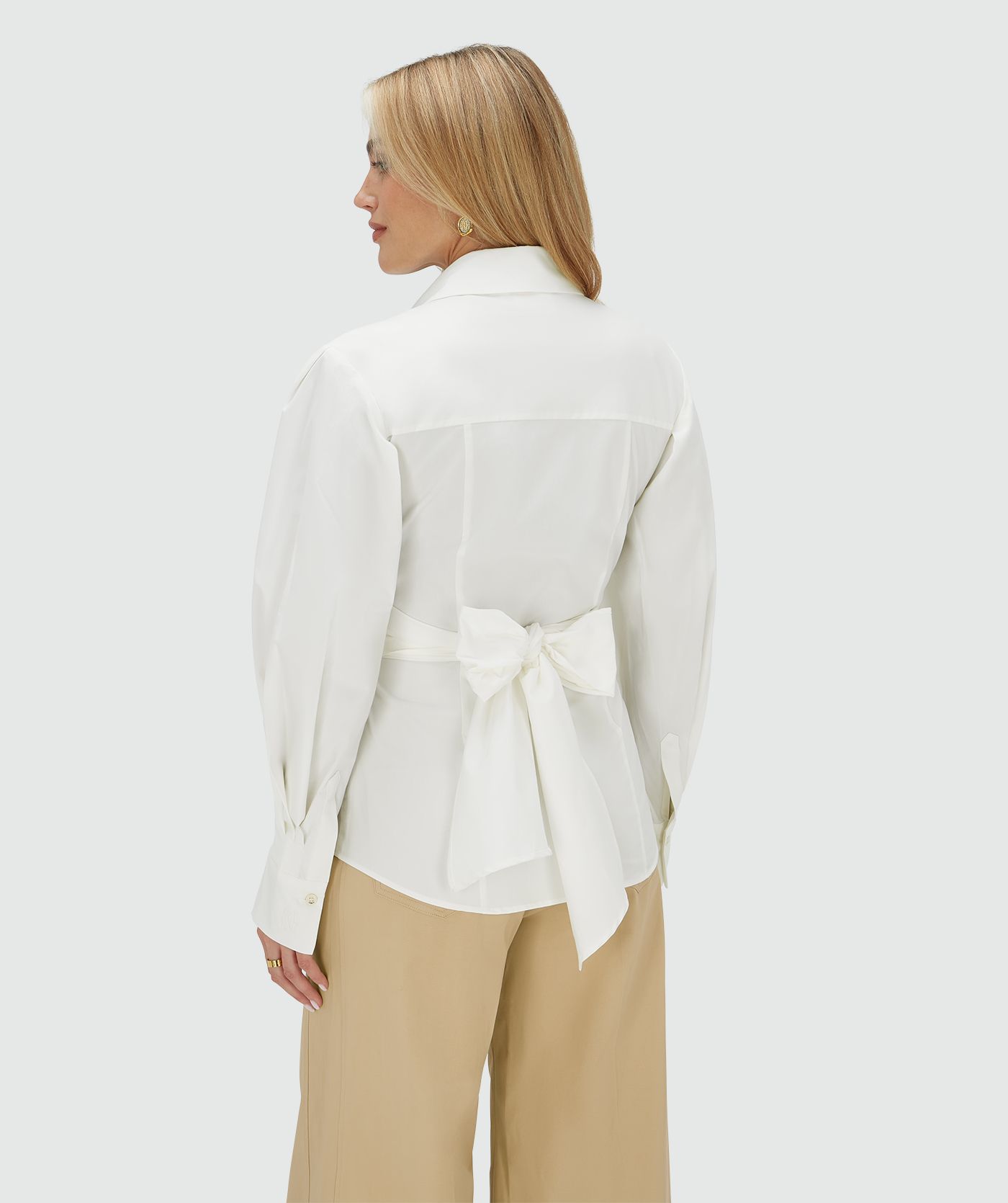 Achteraanzicht van een model in een fitted blouse in het wit met strikdetail op de achterkant