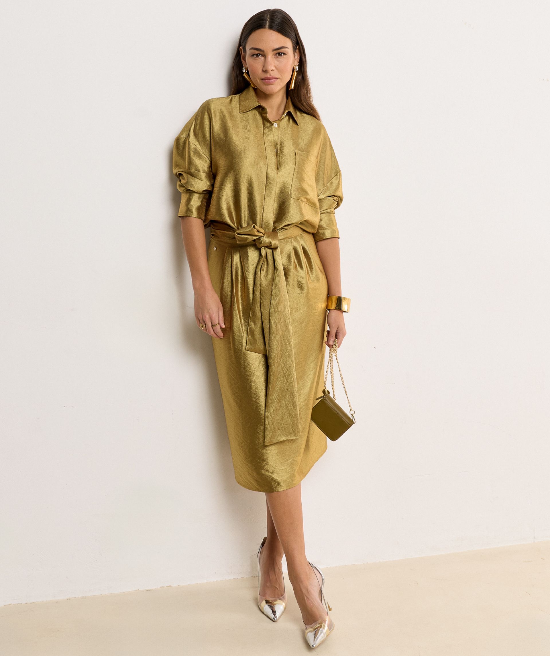 Model draagt een Dark Gold blouse met lange mouwen, knoopsluiting en een borstzak. De blouse heeft een glans