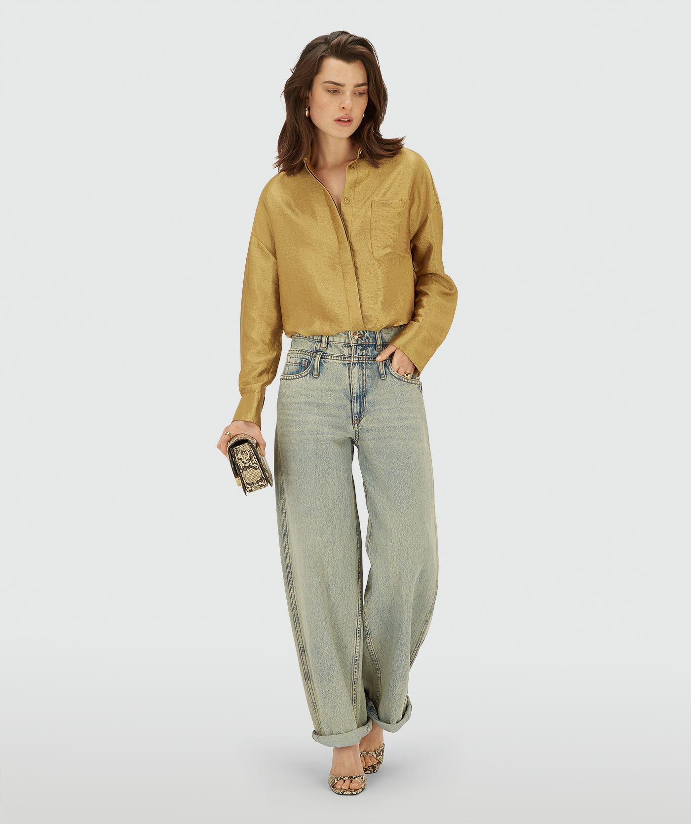 Model draagt een Dark Gold blouse met lange mouwen, knoopsluiting en een borstzak. De blouse heeft een glans