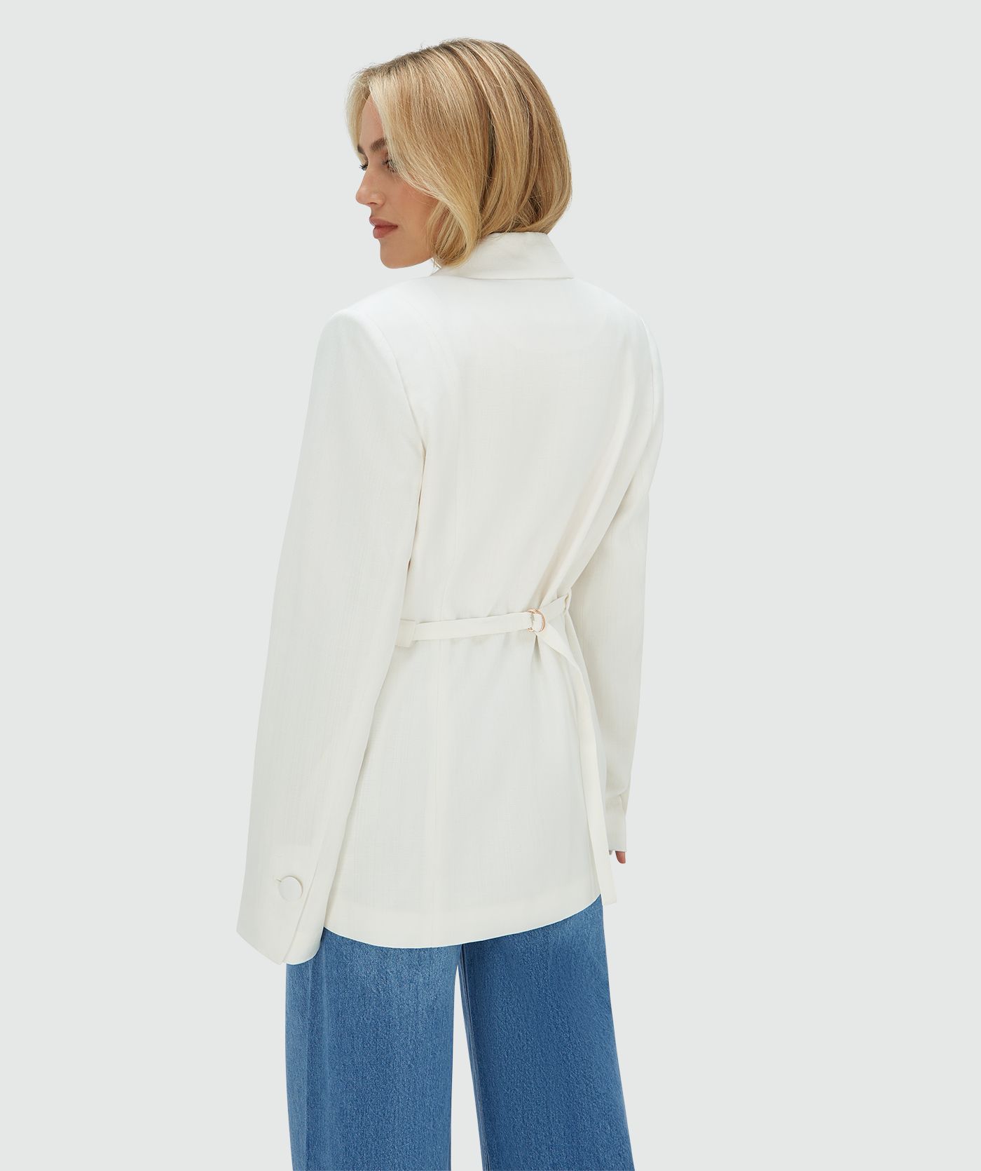 Achteraanzicht van het model in een Off White oversized blazer, waarbij de ceintuur aan de achterzijde zorgt voor een getailleerd effect