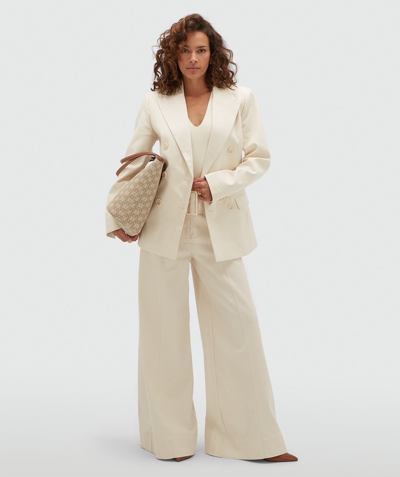 Model draagt gebroken witte high waisted wide leg jeans met een grote riem.