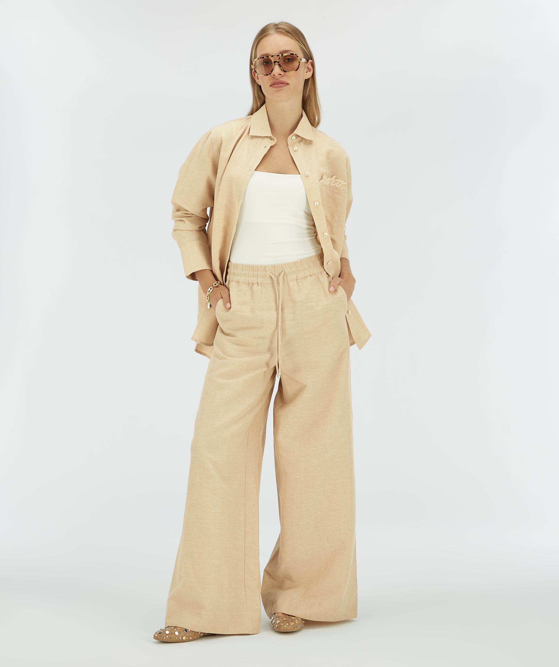 Model draagt een beige blouse met een zakje op de borst.