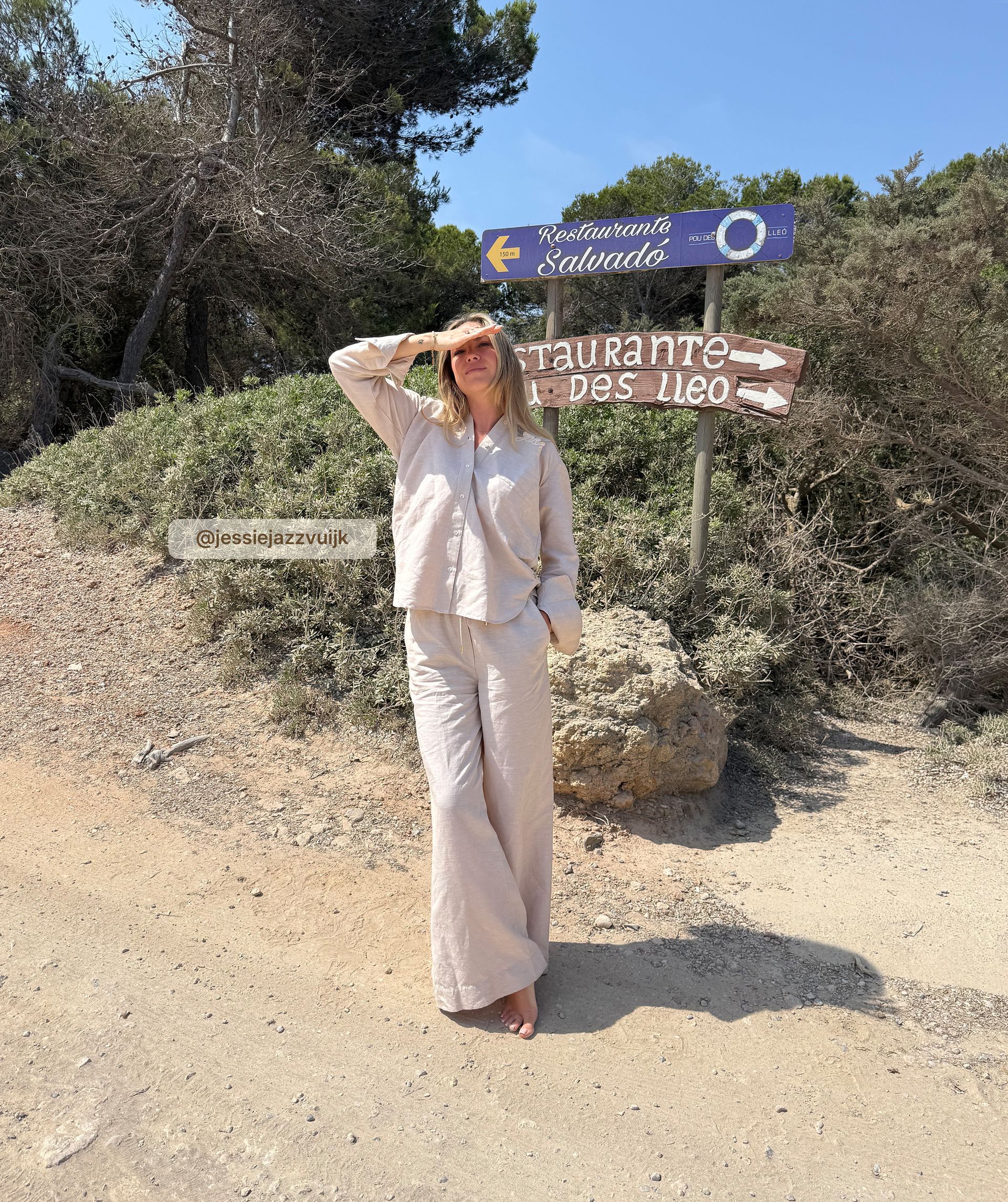 Infleuncer draagt de beige linnen look blouse met de bijpassende broek en staat op het strand