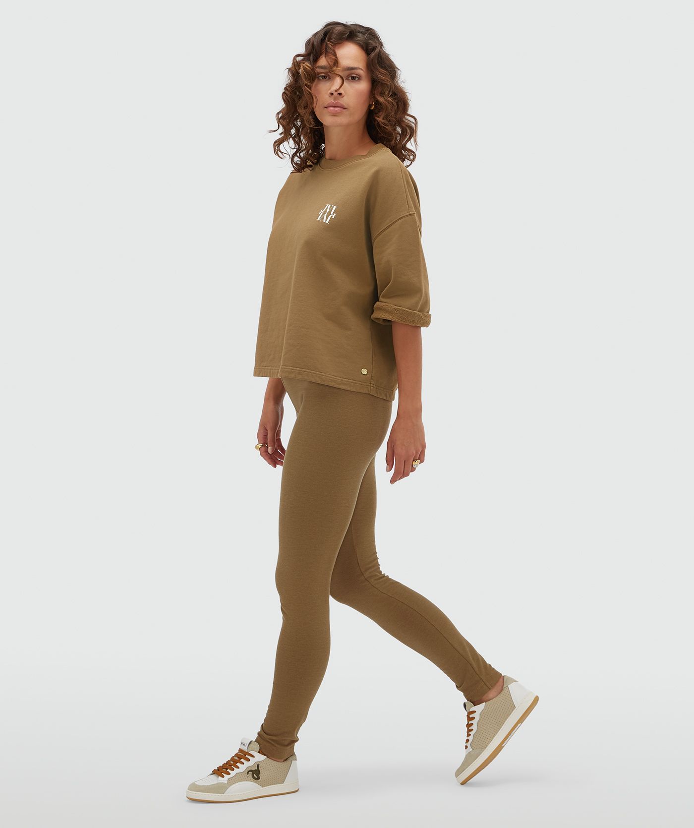 Model draagt een strakke lagging in de kleur Khaki gecombineerd met een sweater met korte mouwen.