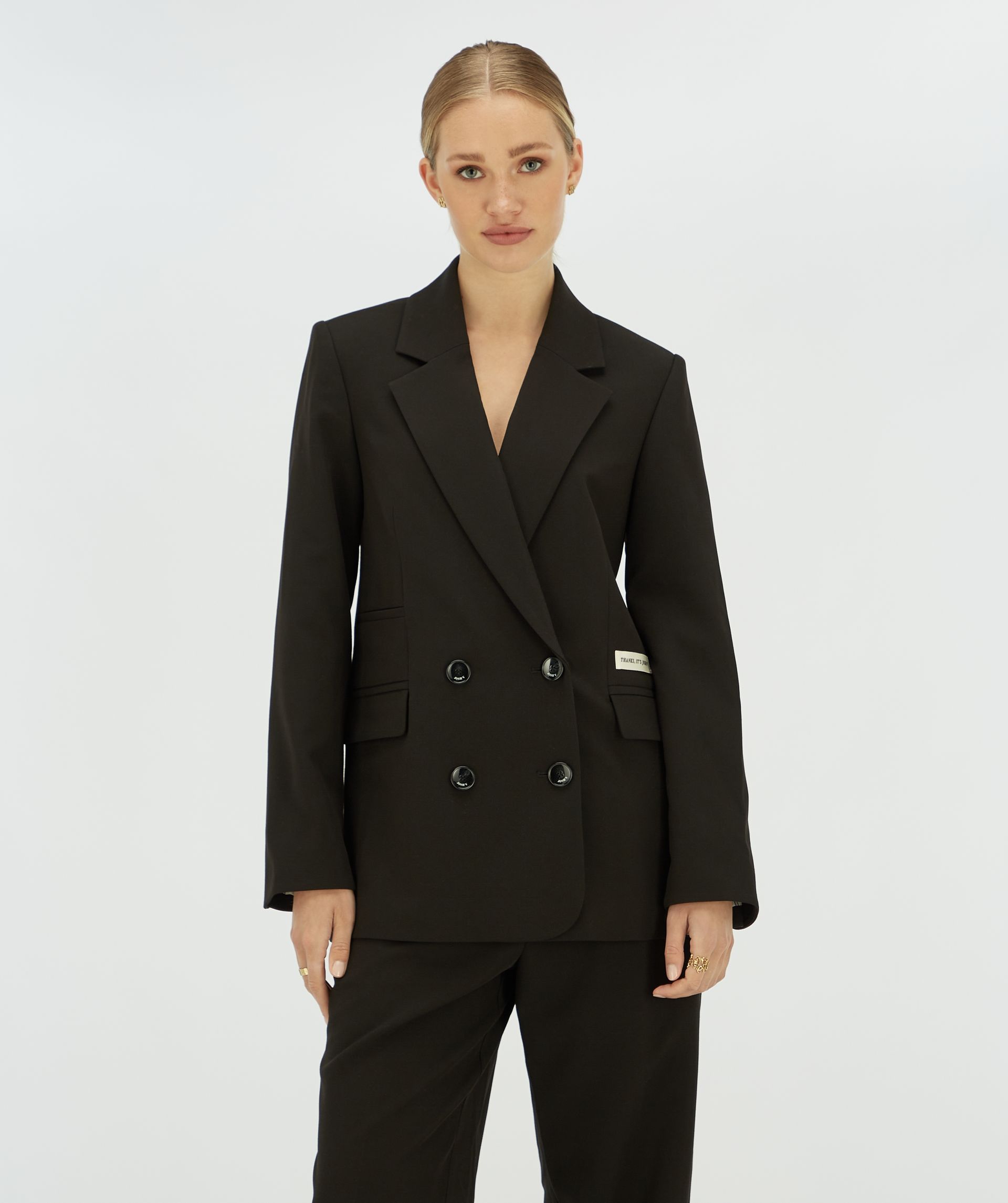 Model draagt een zwarte blazer met aan de zijkant een Josh v label.