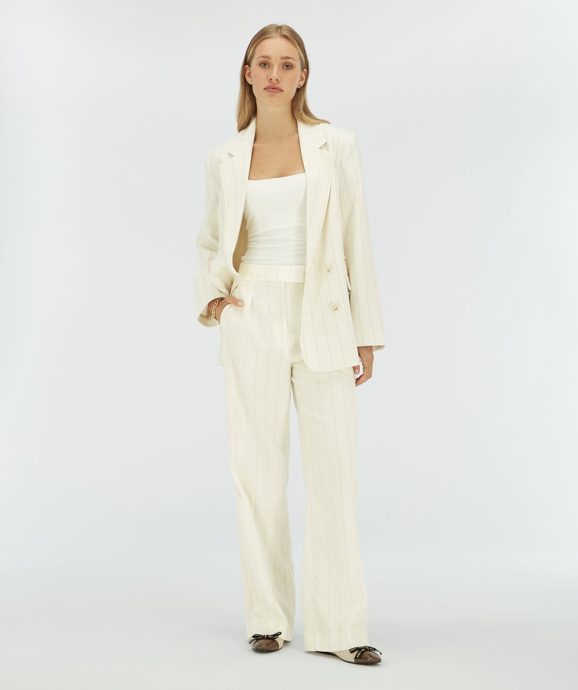 Model draagt een witte blazer met een beige krijtstreepje.